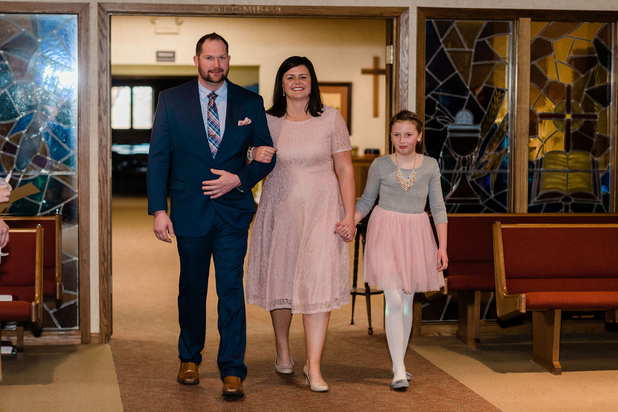 Groom, bride, and child walking into wedding ceremony