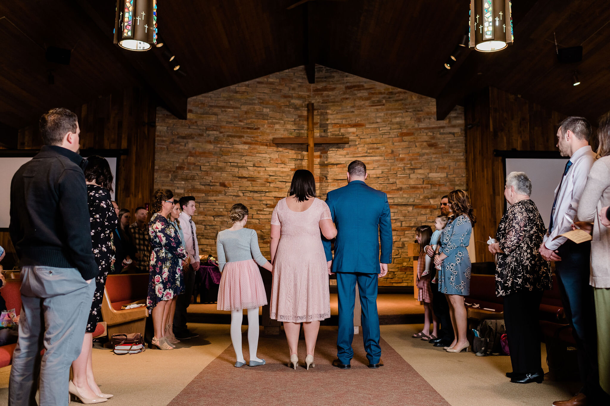 Groom, bride, and child standing at the altar in church