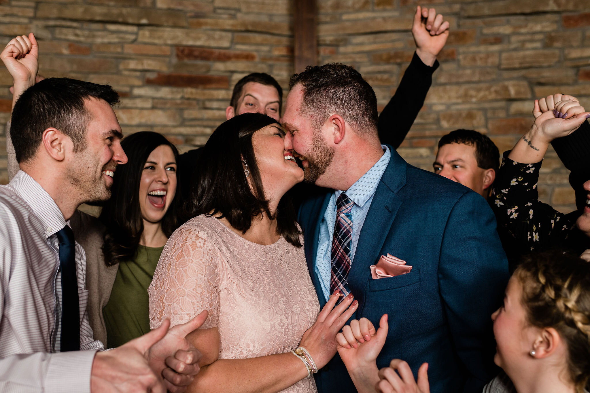 Bride and groom kissing while guests cheer