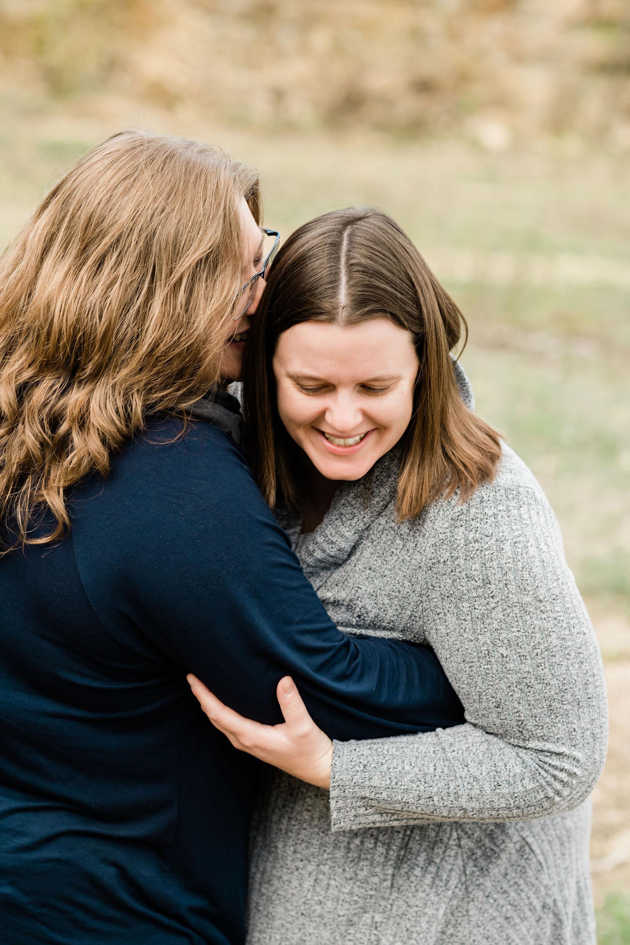 Woman whispers into her wife's ear