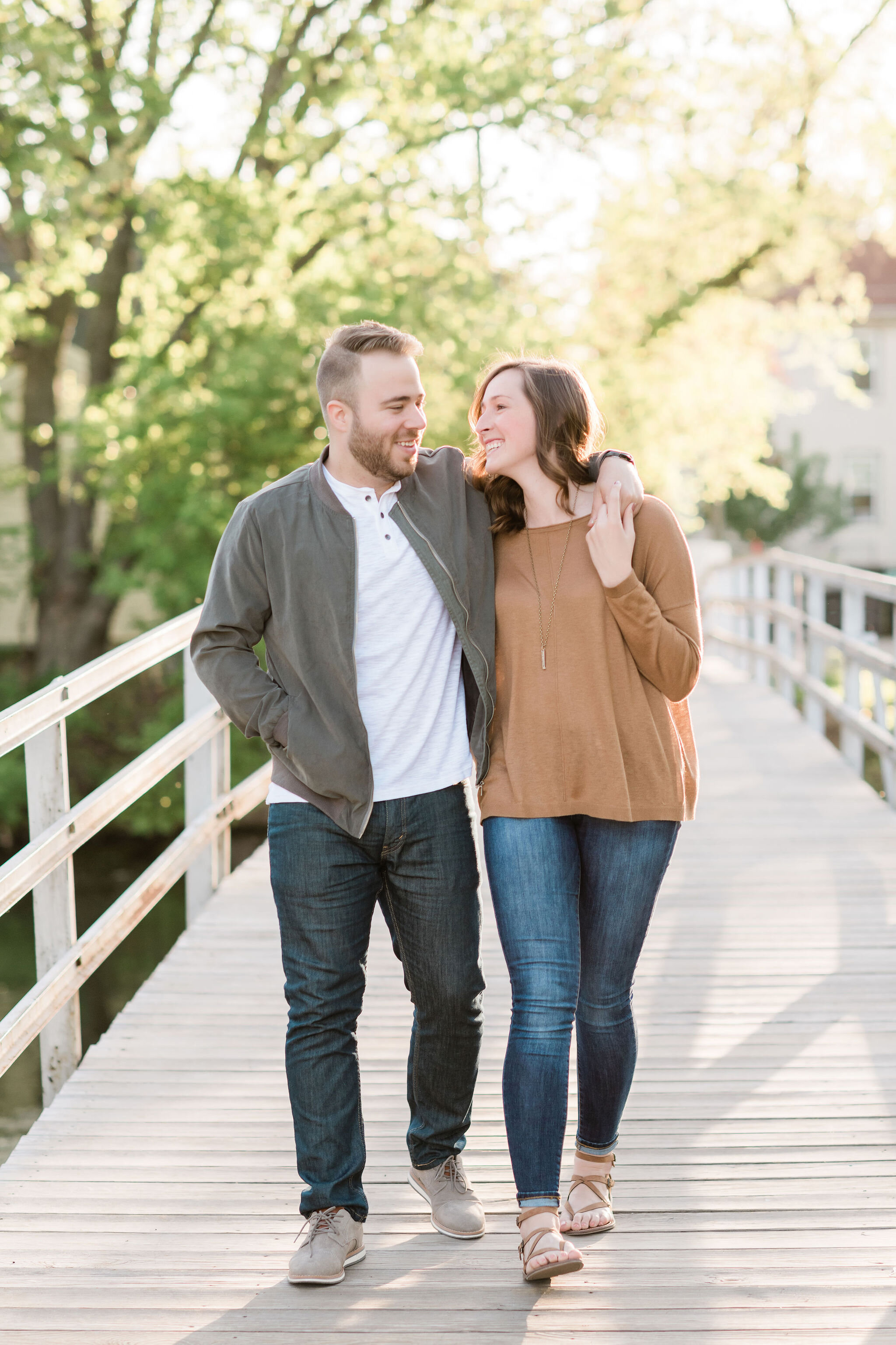 Engaged couple laughing and walking on a bridge