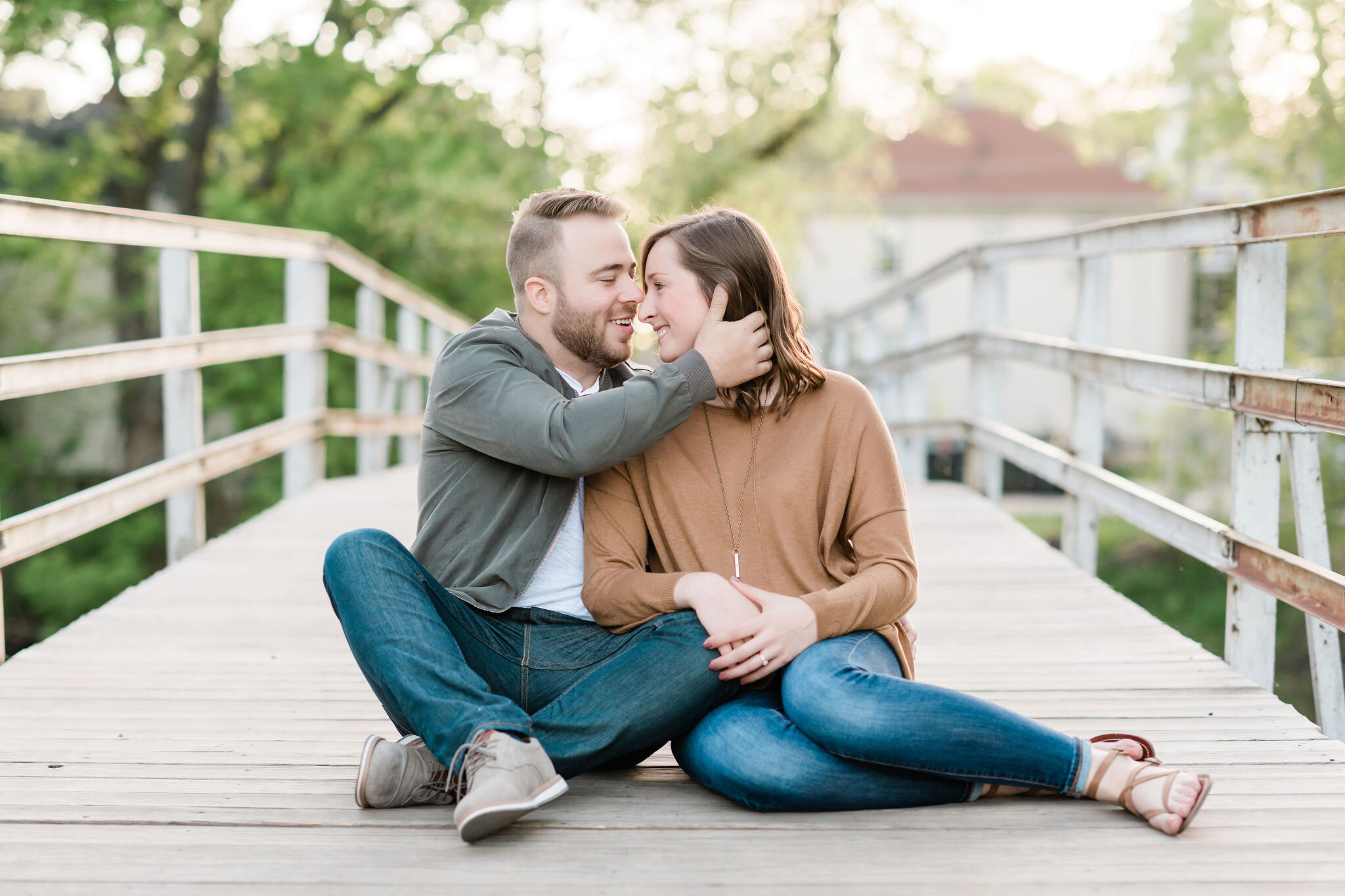 Engaged couple sitting on a bridge