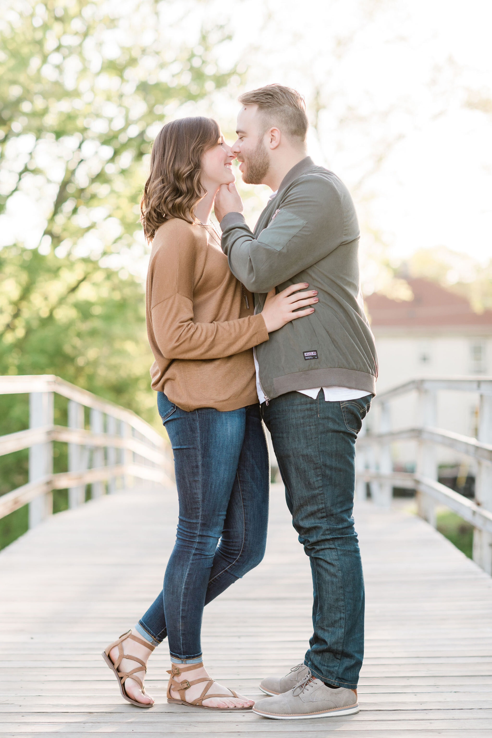 Engaged couple facing each other on a bridge