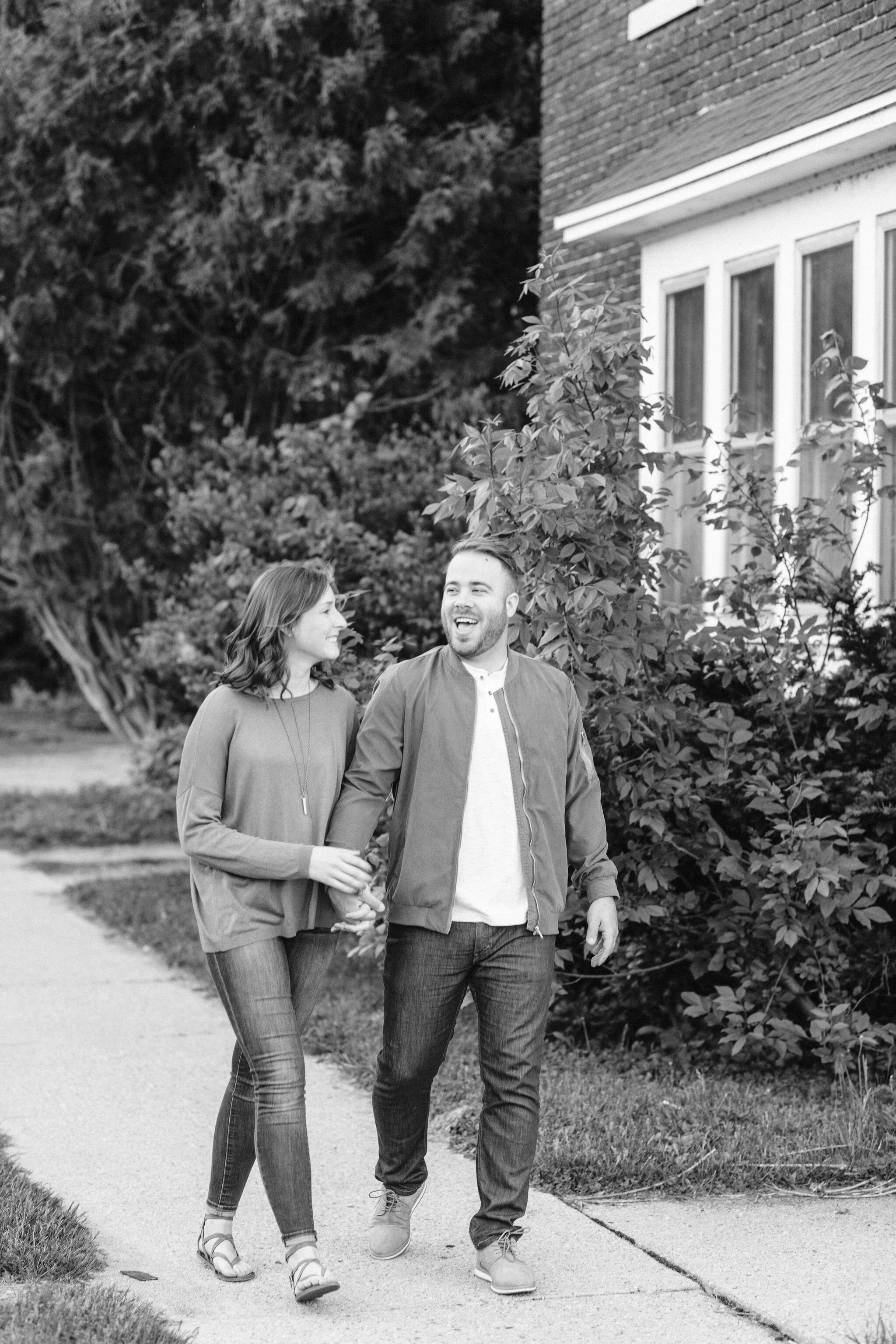 Engaged couple laughing and walking down the sidewalk