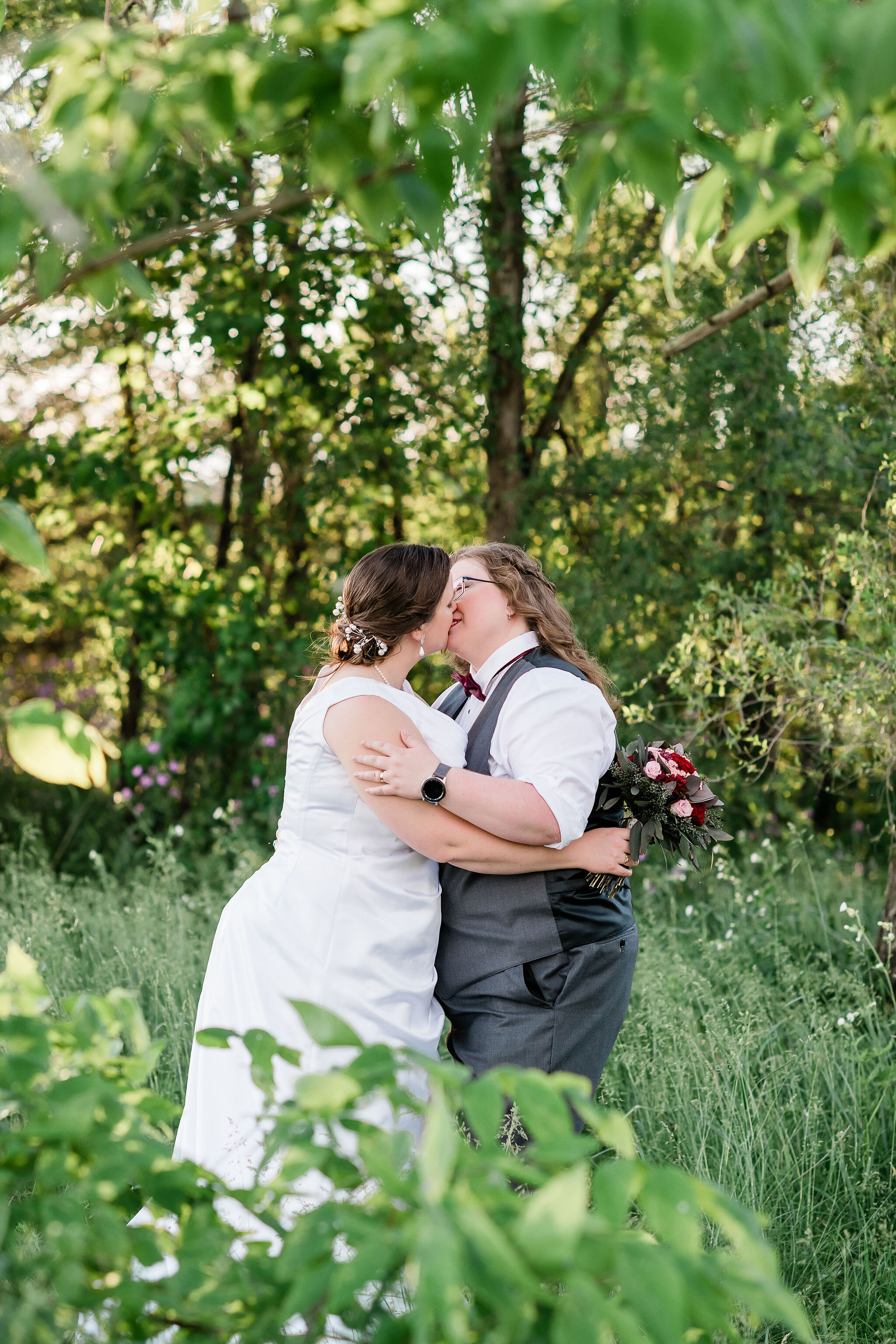 Bride and bride kissing in the woods