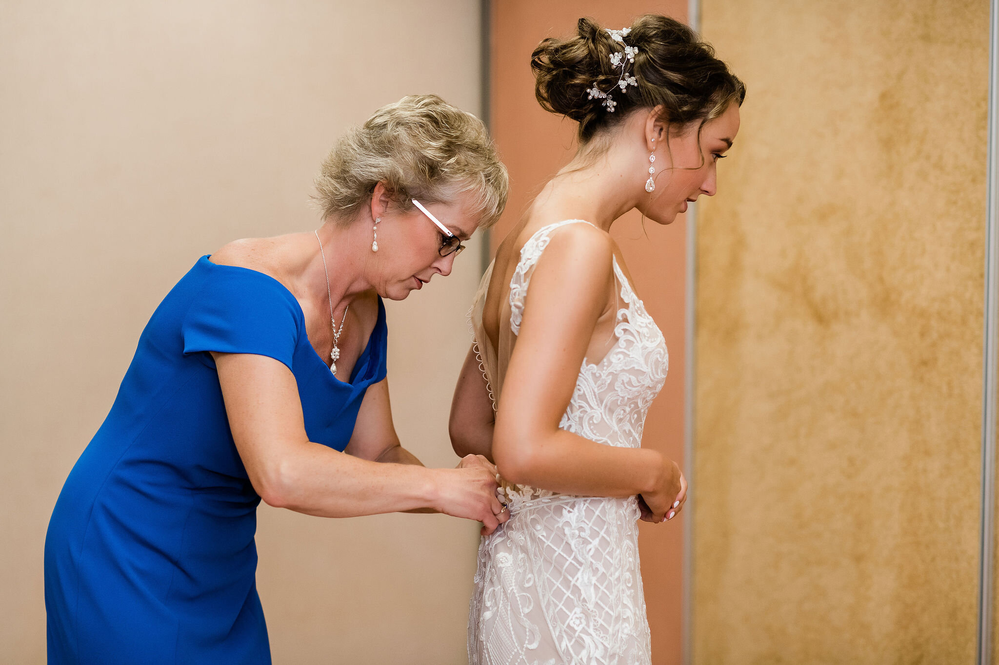 Mother of the bride fastening up wedding dress