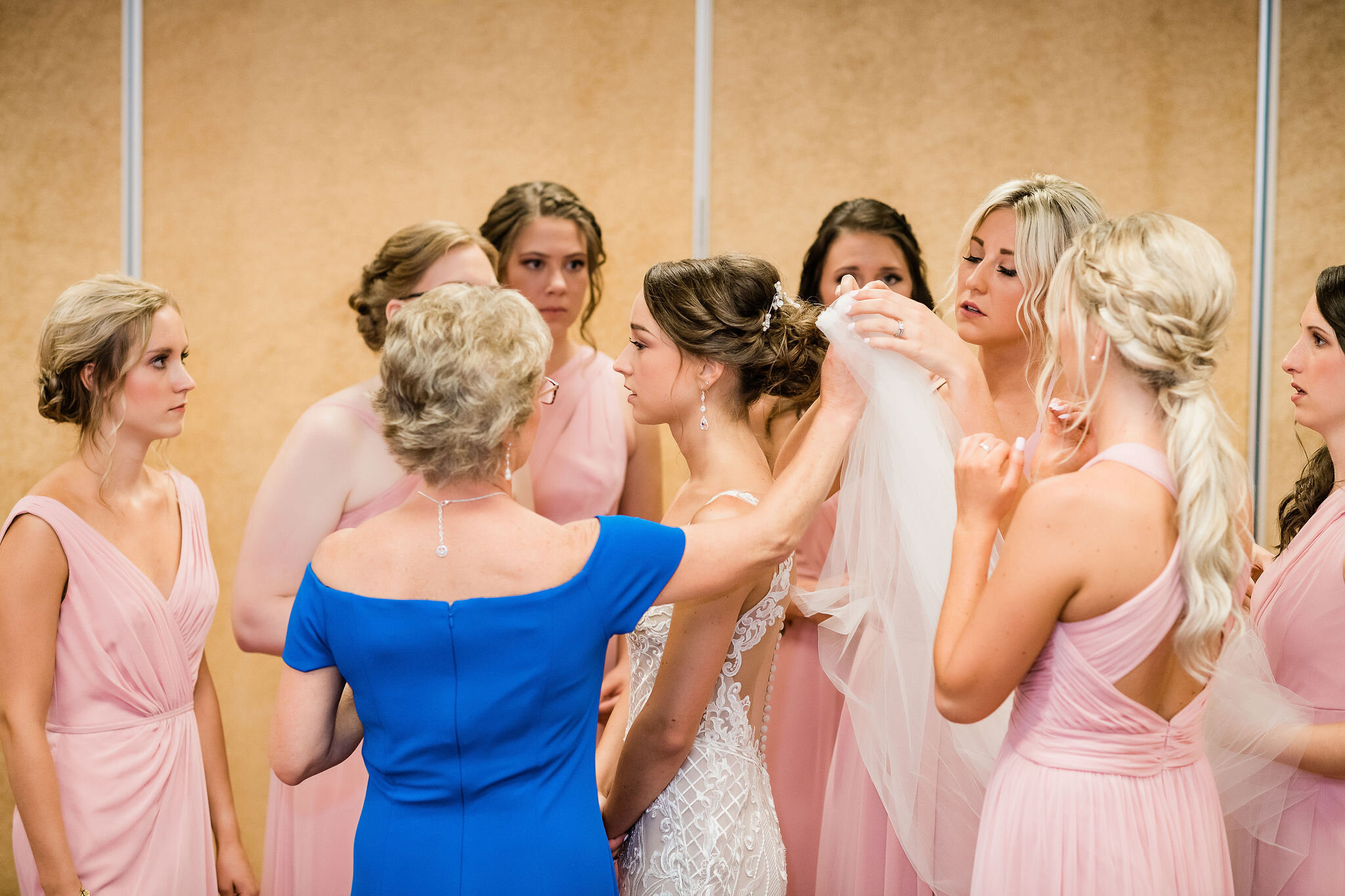 Mother of the bride and bridesmaids putting the bride's veil on