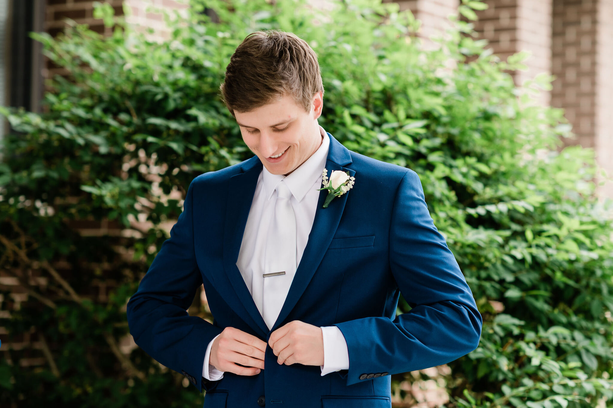 Groom buttoning up his suit jacket