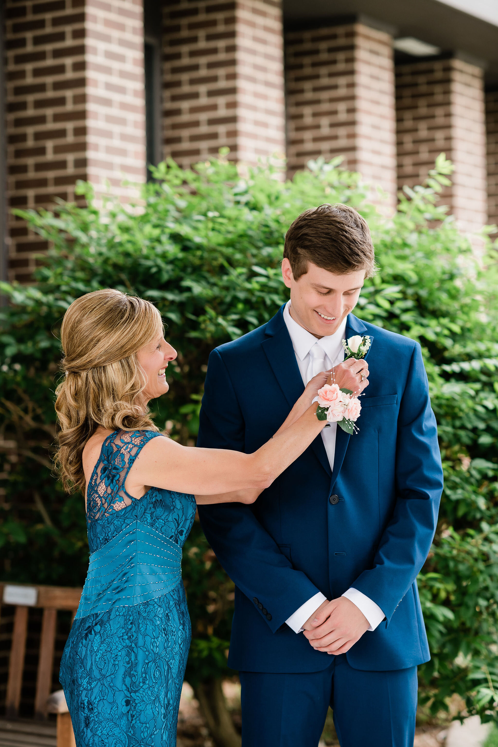 Mother of the groom pinning the groom's boutonniere on him