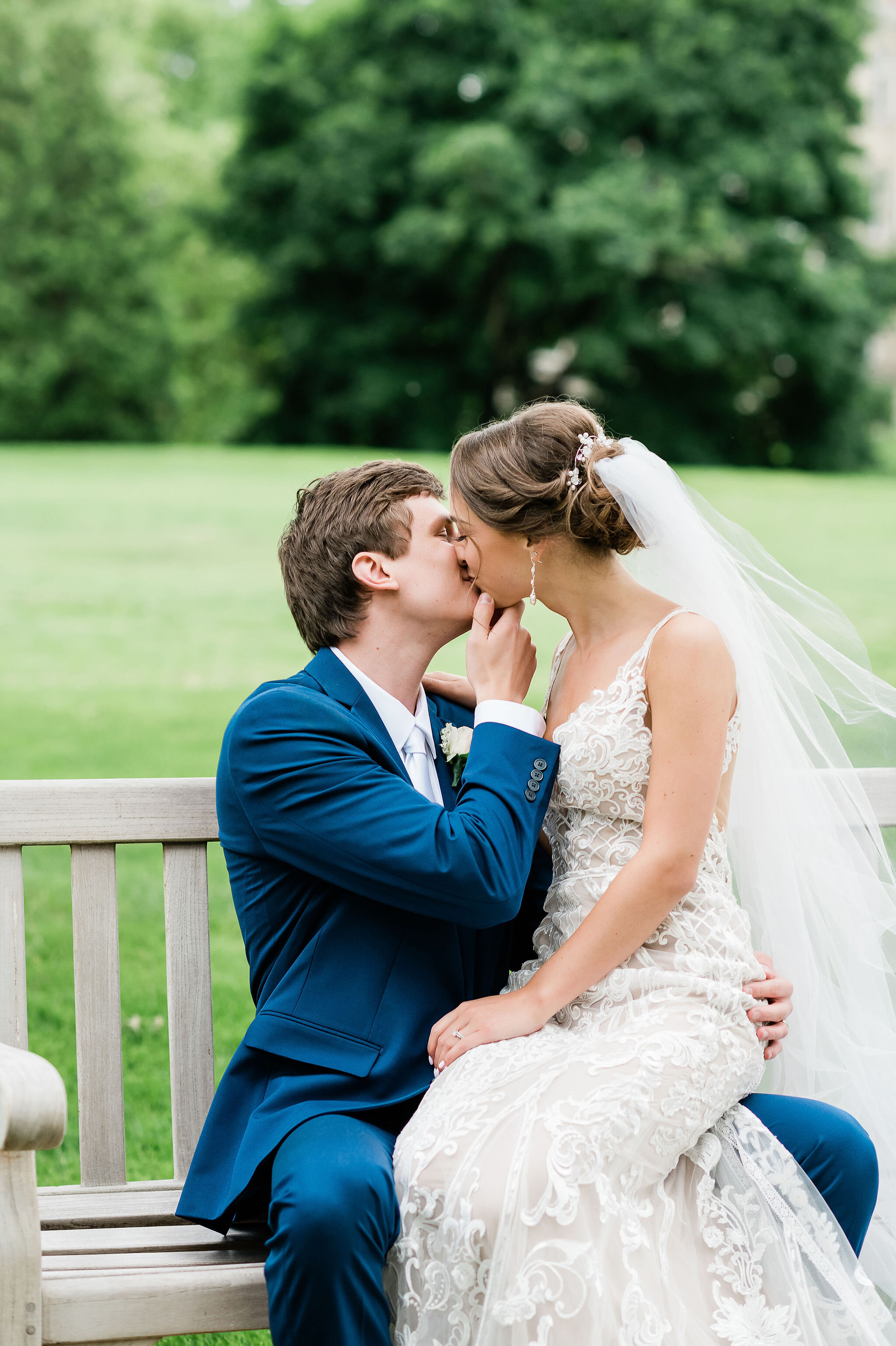 Bride and groom kissing on a bench
