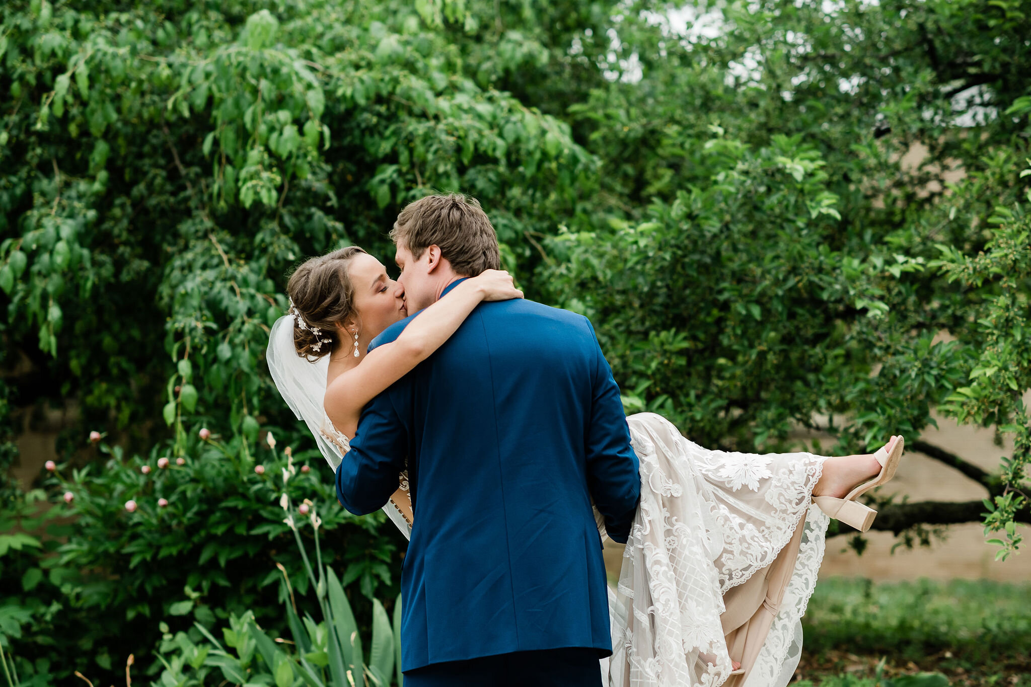 Groom carries bride as they kiss