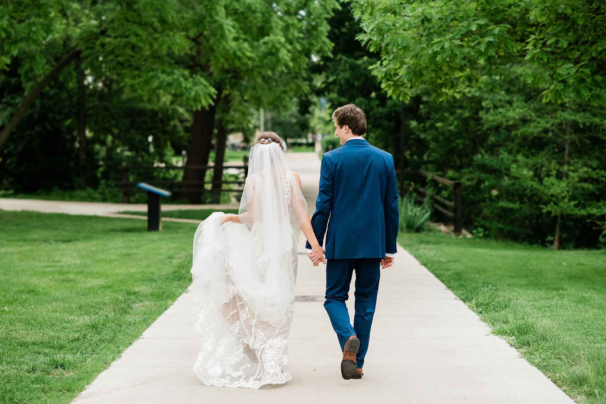 View from behind of bride and groom walking down the sidewalk