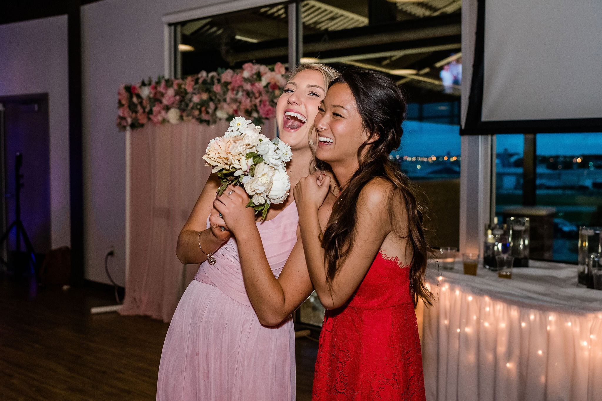 Bridesmaid cheers with a friend after catching the bride's bouquet