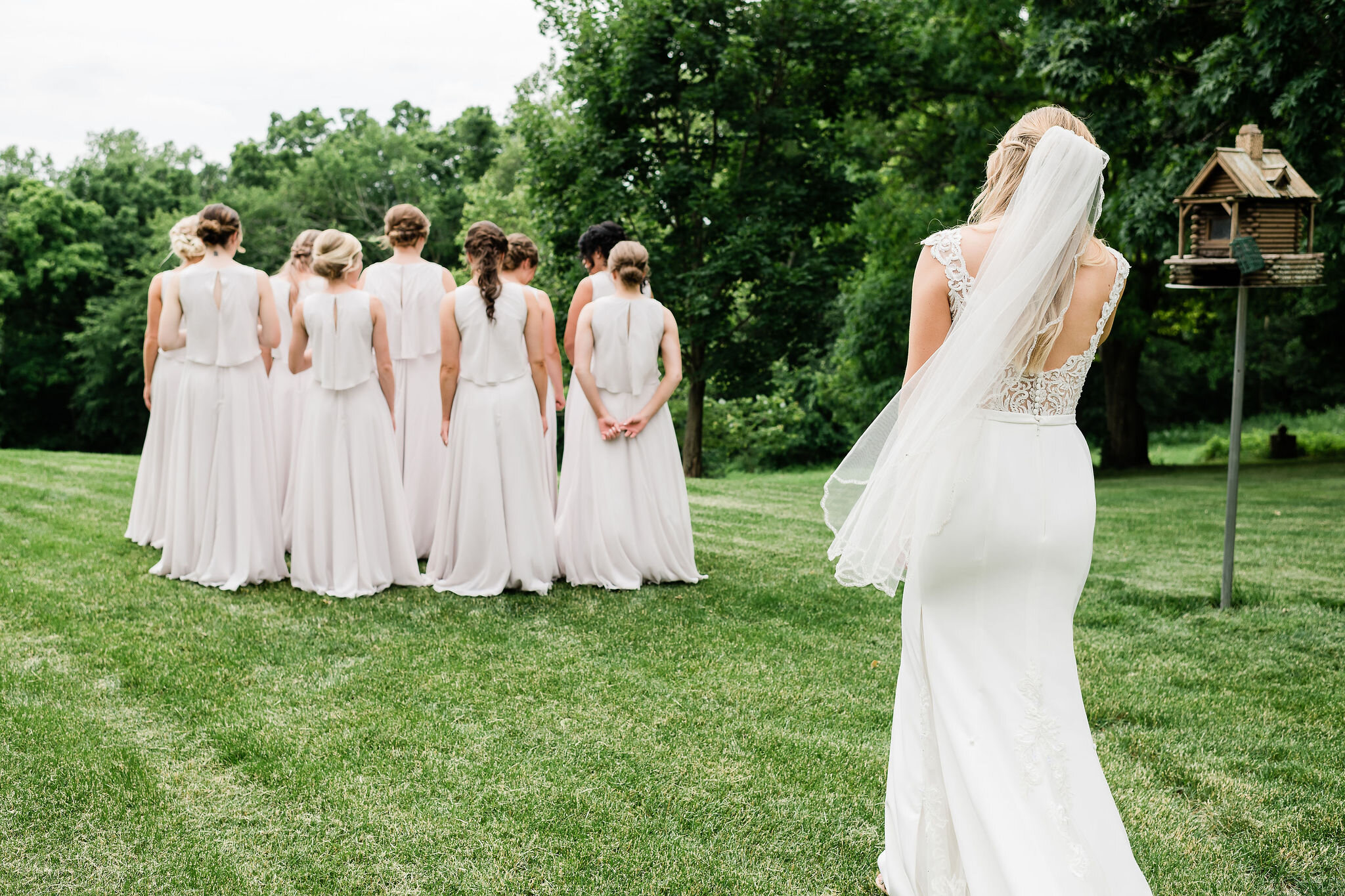 Bride standing behind bridesmaids for their first look