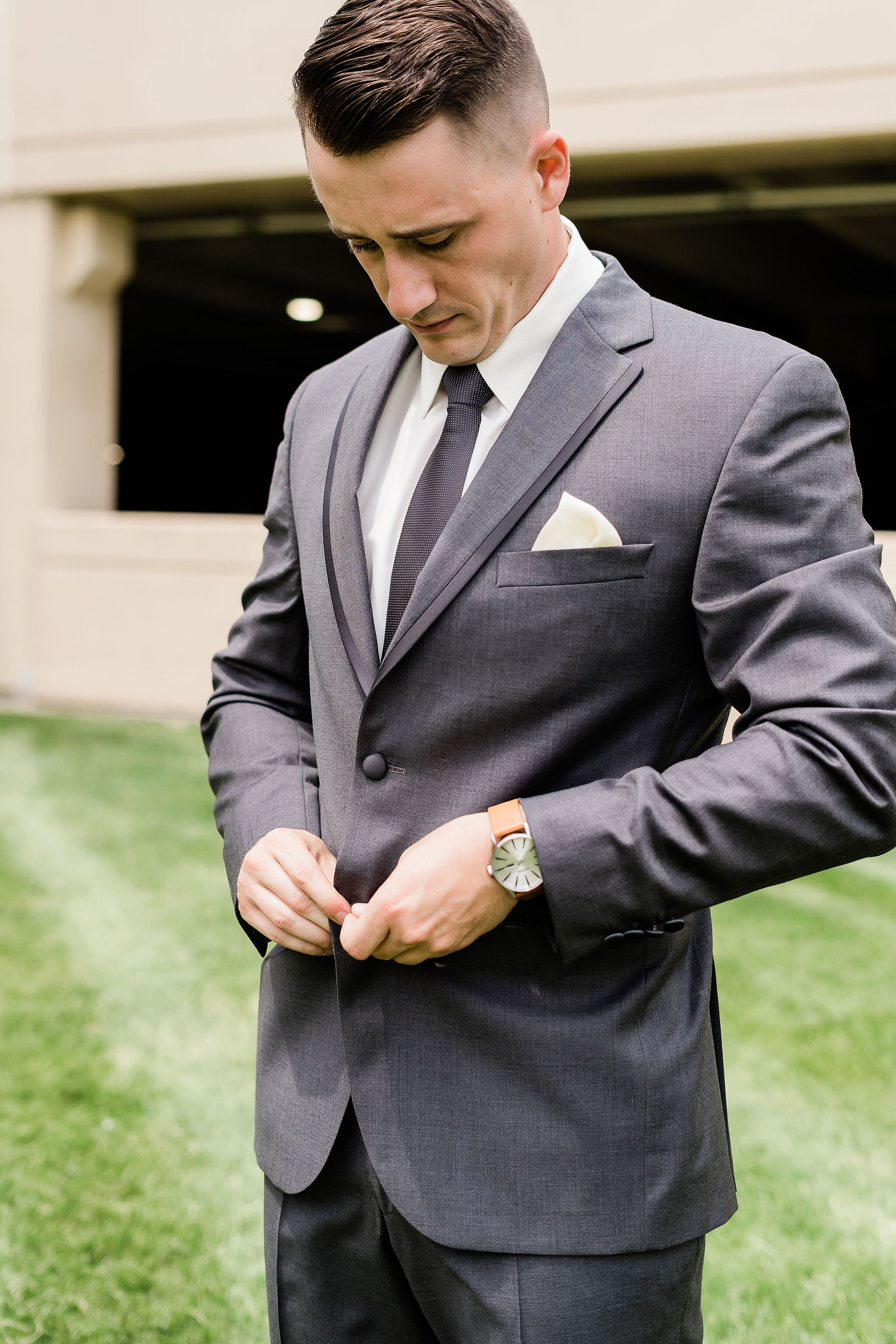 Groom buttoning his suit jacket