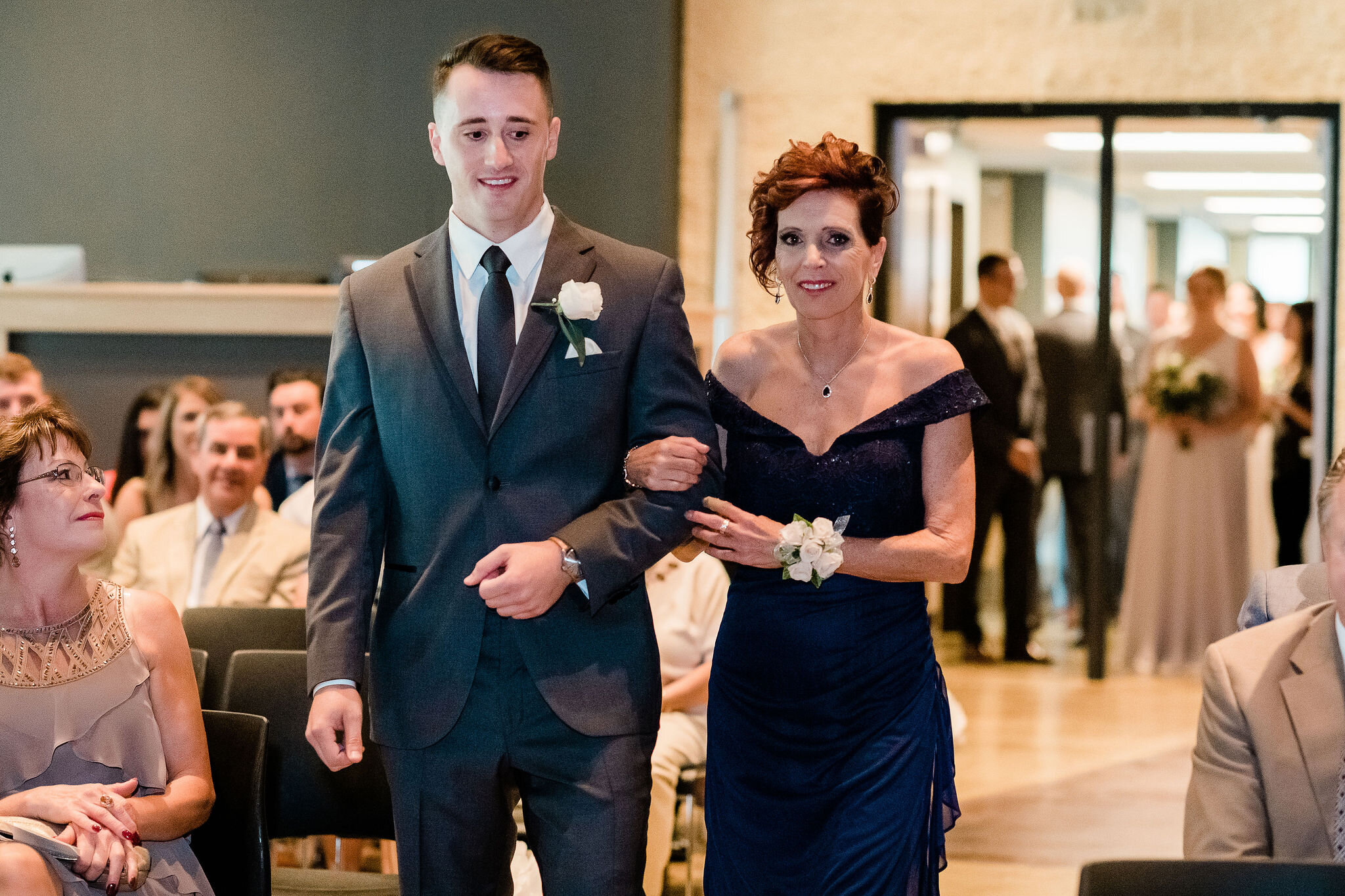 Groom walking down the aisle with his mother