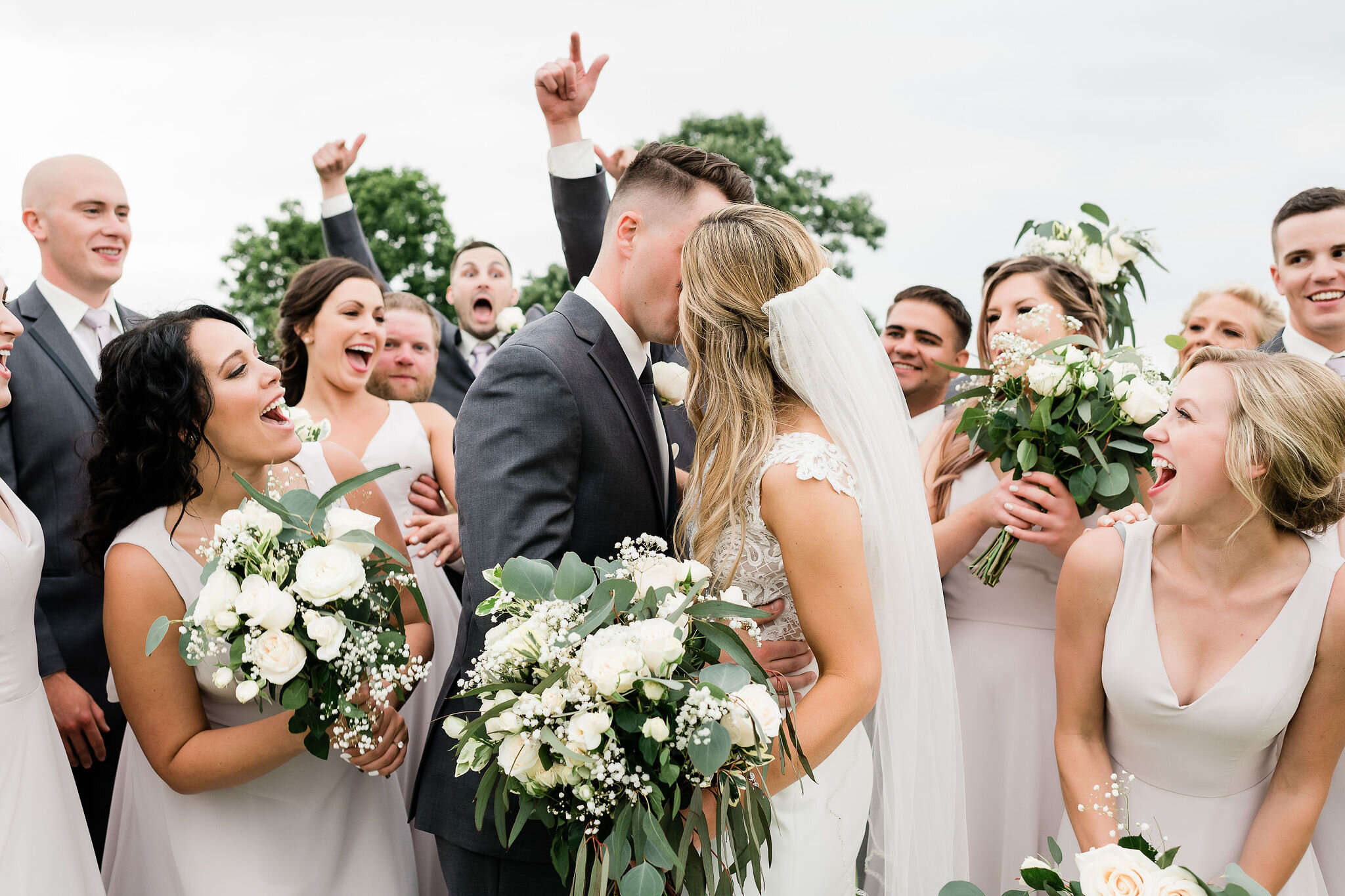 Bride and groom kiss while wedding party cheers