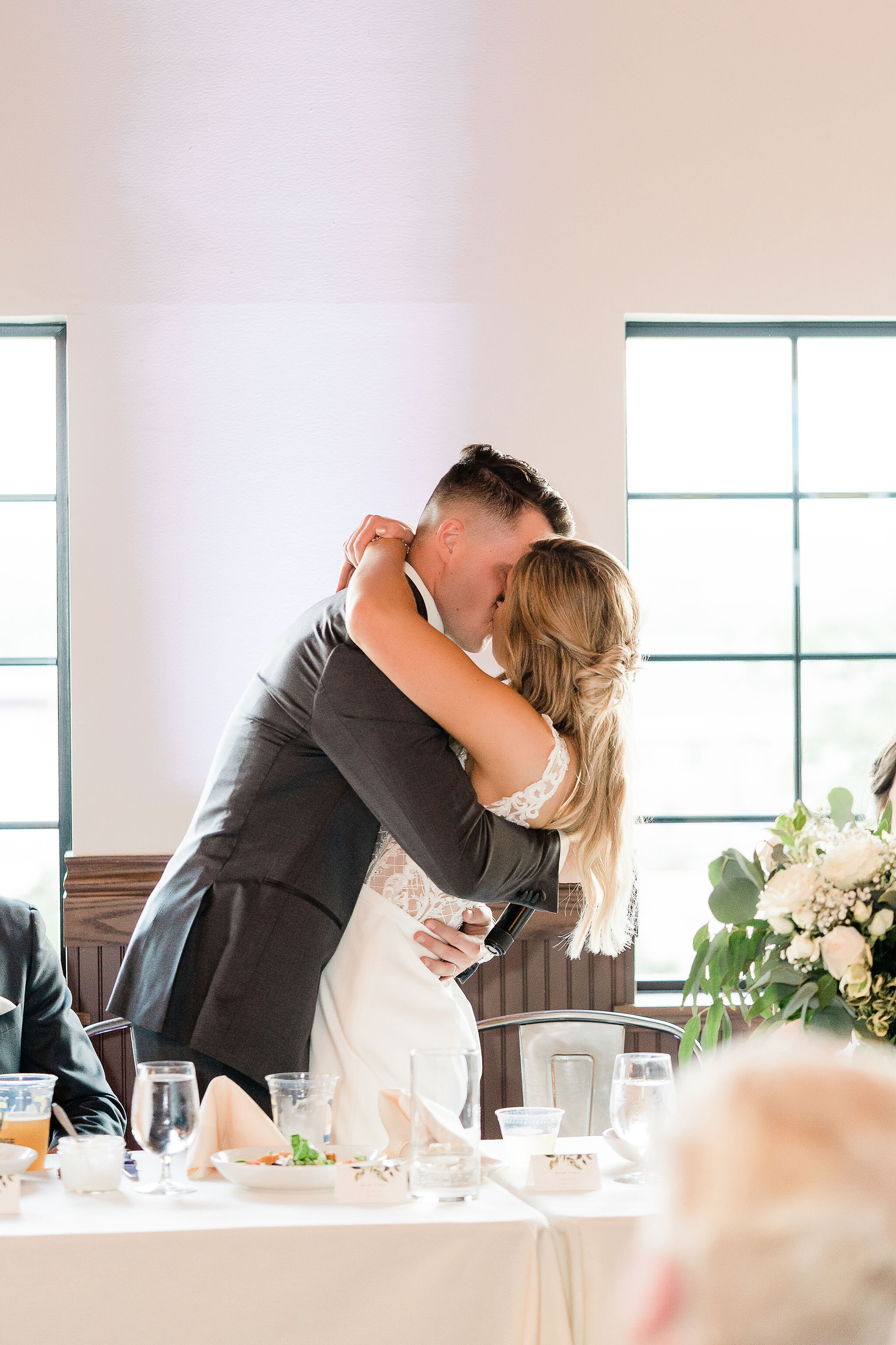 Bride and groom kissing at the head table