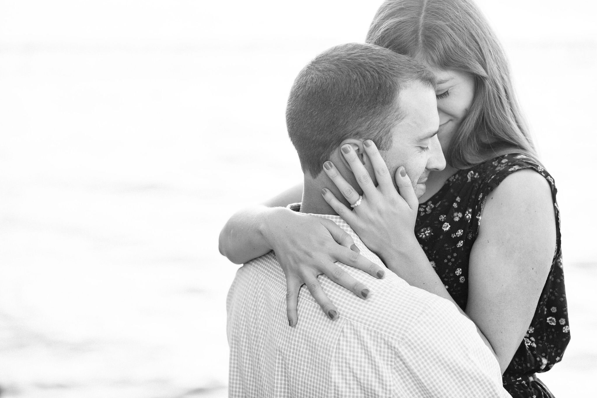 Woman wraps her arms around her fiancé as he picks her up