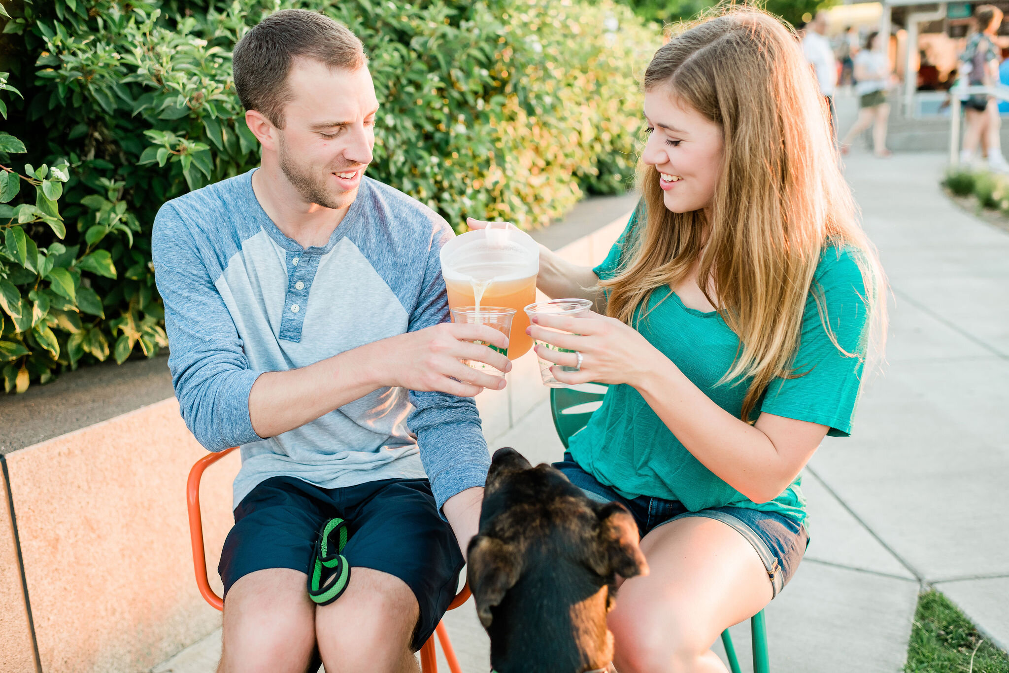 Engaged couple pouring beer from a pitcher as their dog watches