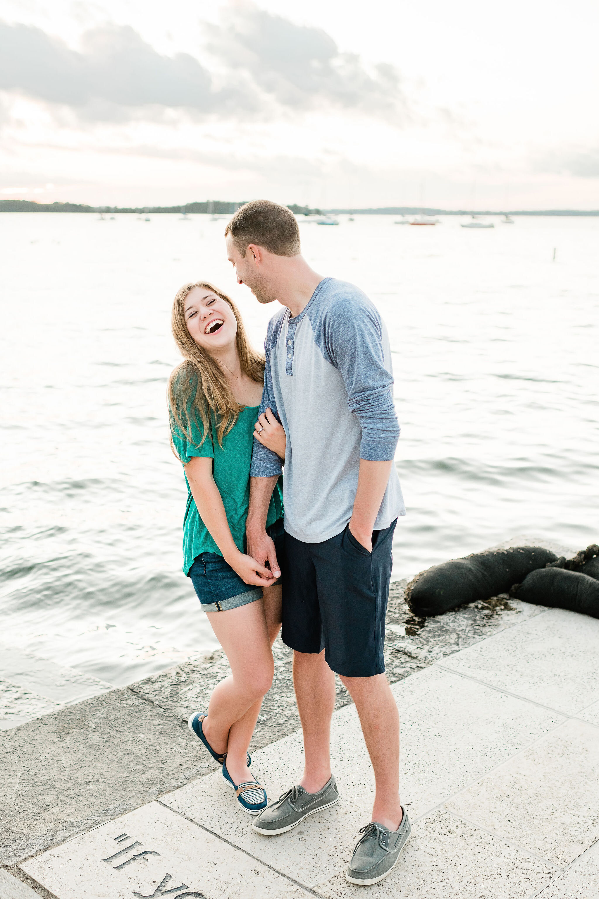 Engaged couple laughing on a dock