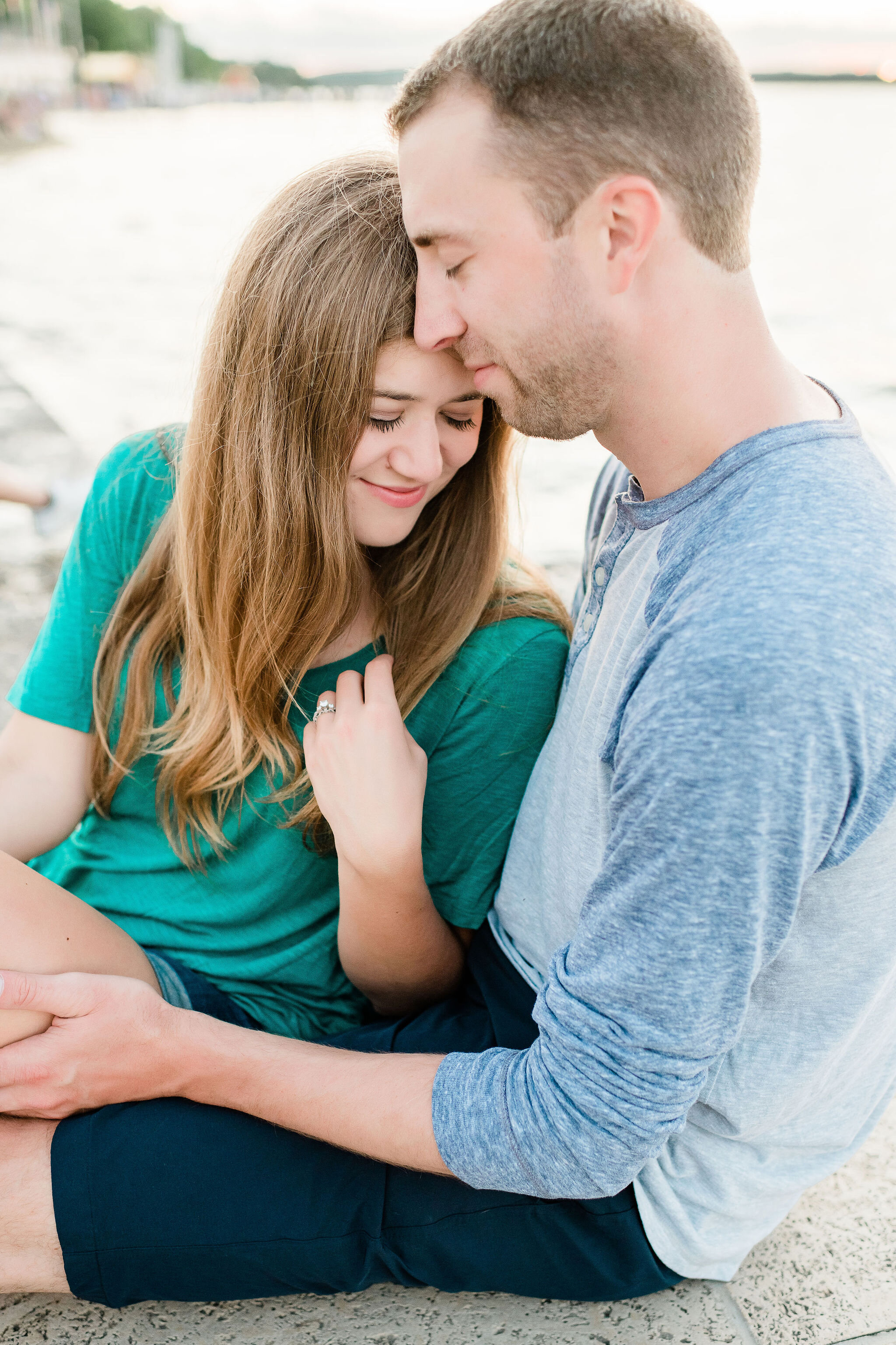 Engaged couple snuggling on a dock