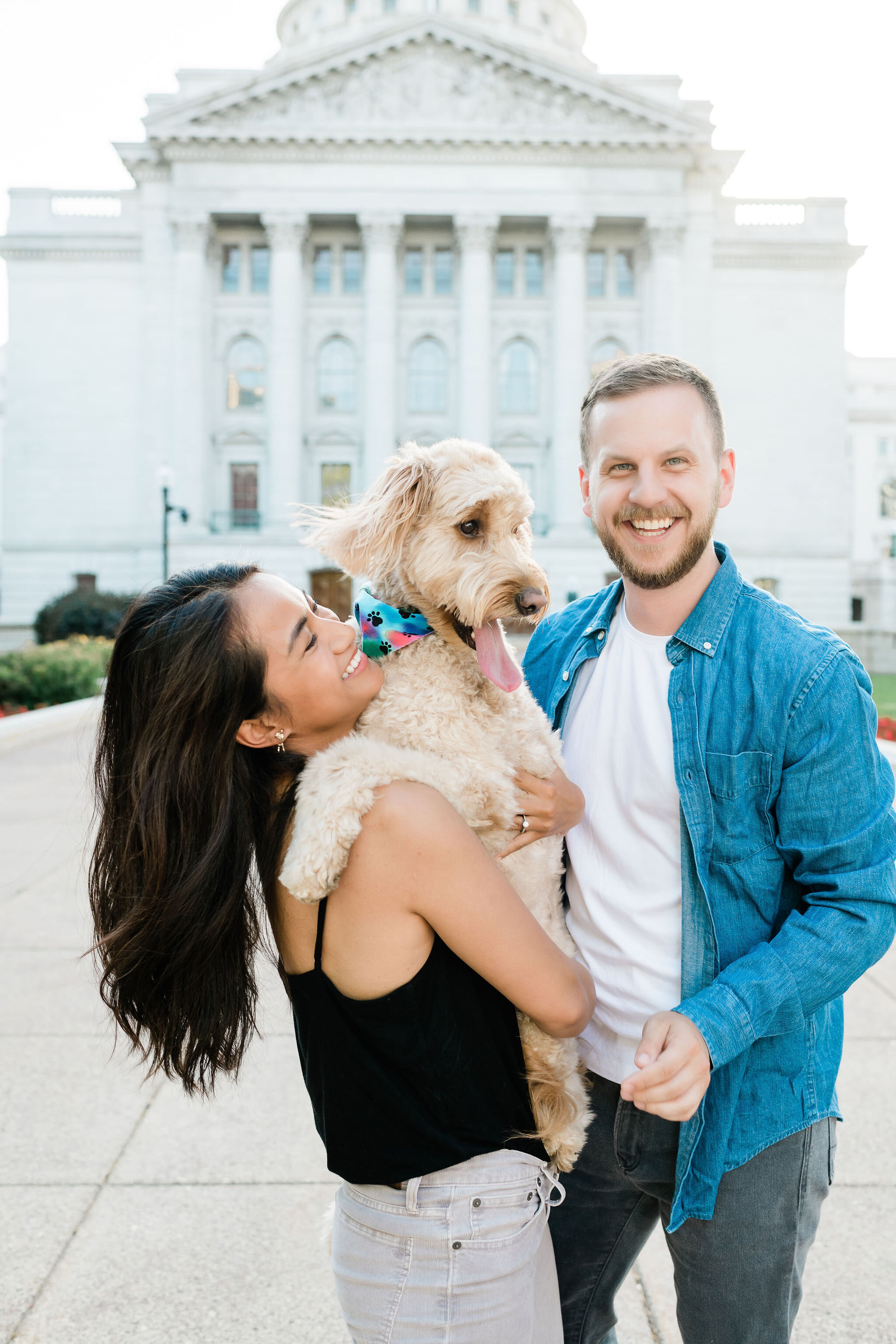 Engaged couple and their dog in front of the Wisconsin State Capitol in Madison, WI