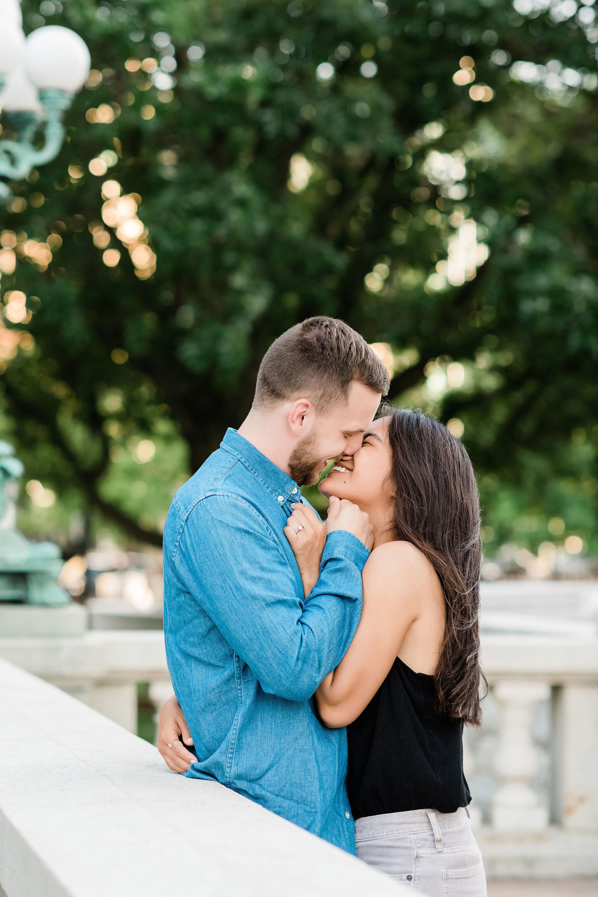 Engaged couple cuddling in front of a lamp post