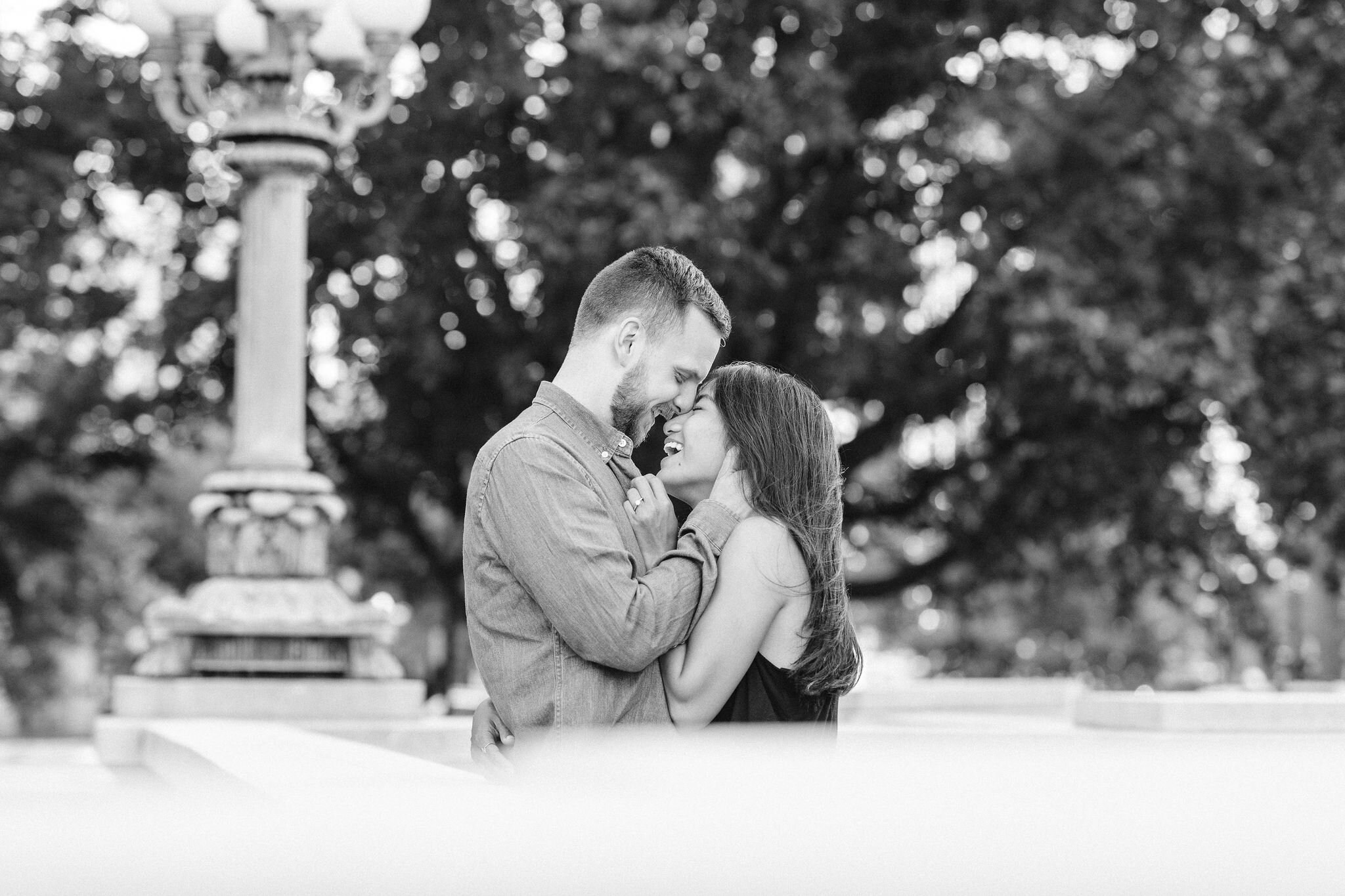 Engaged couple cuddling in front of a lamp post