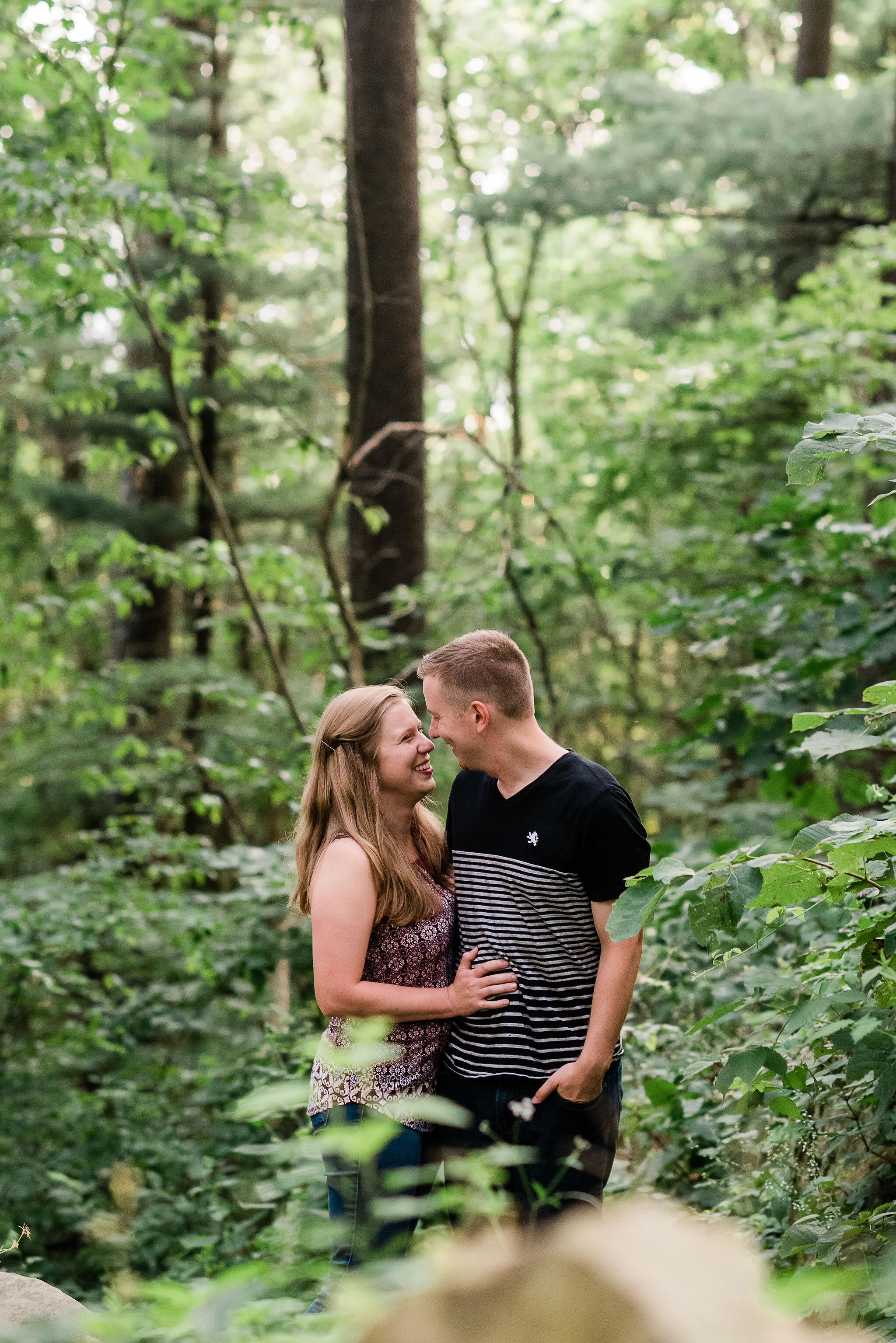 Engaged couple looking at each other in the woods
