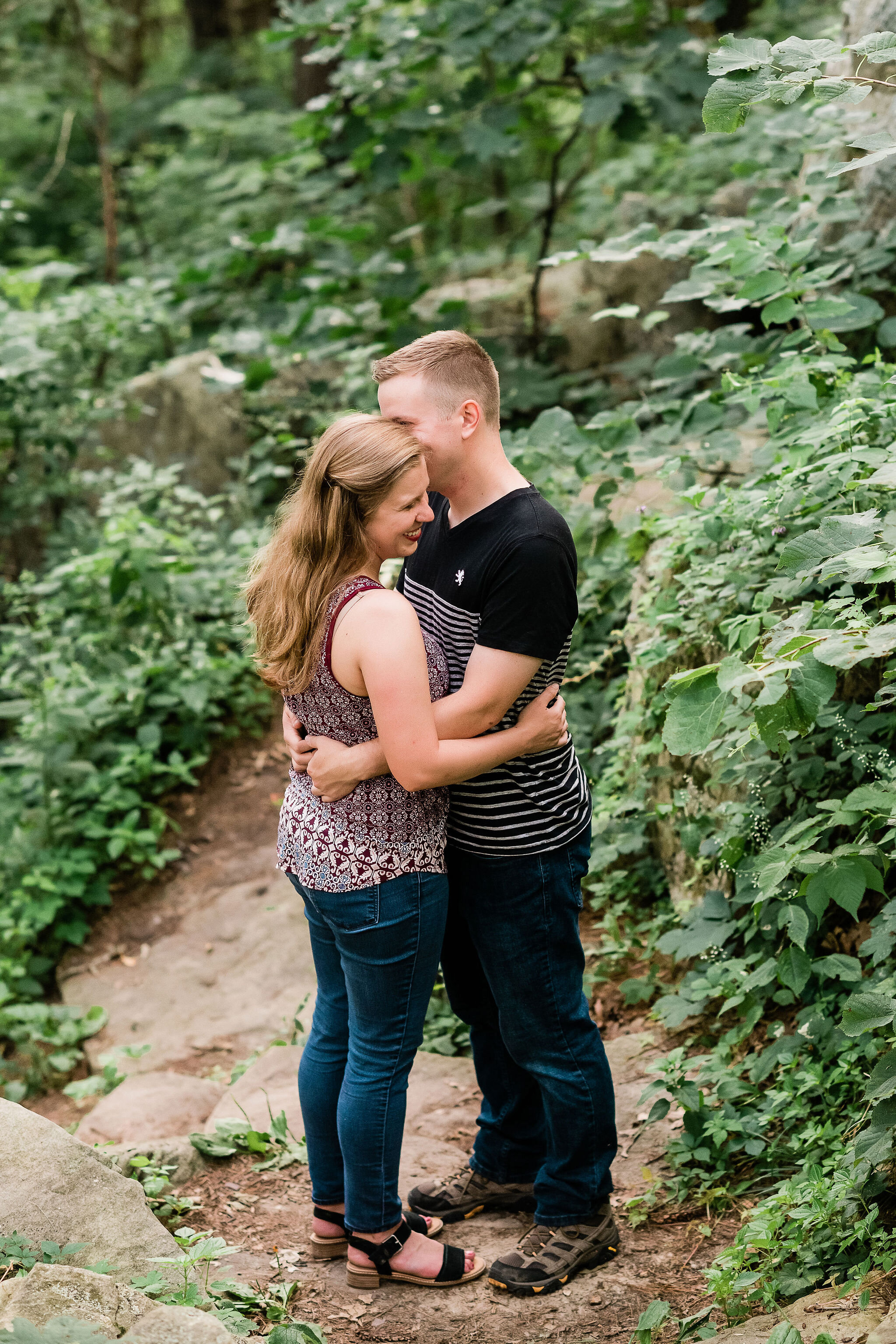 Engaged couple hugging in the woods