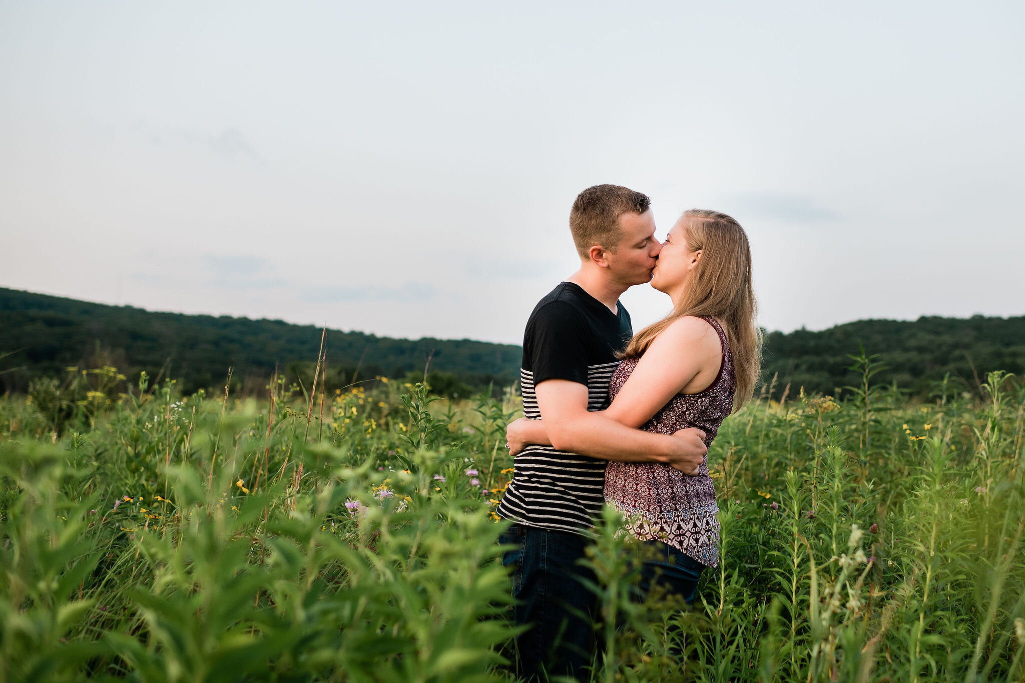 Engaged couple kissing in a field