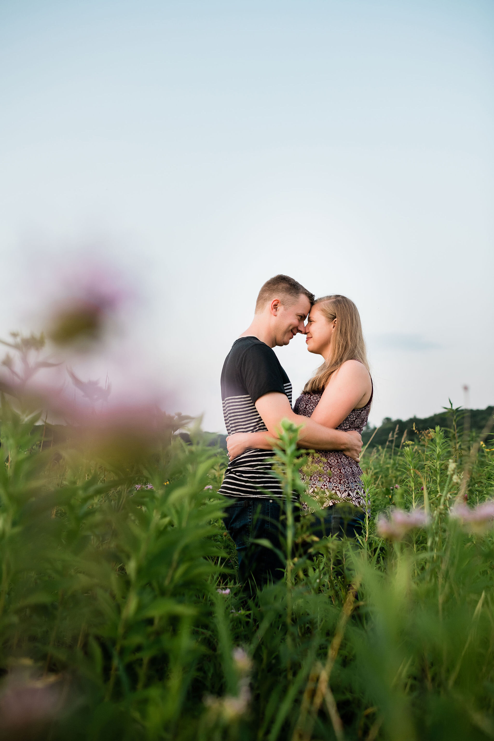 Engaged couple forehead to forehead in a field