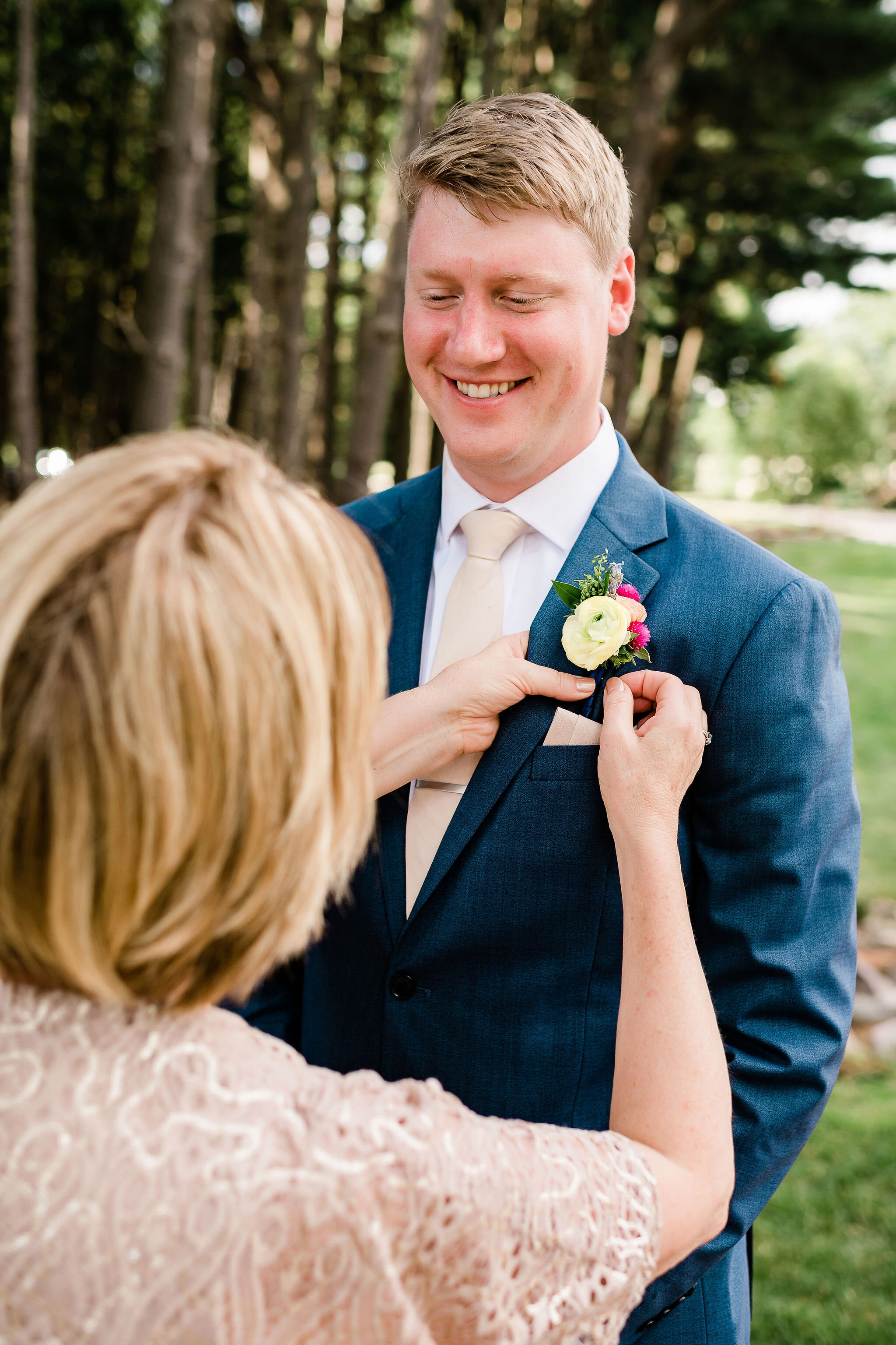 Mother of the groom pinning groom's boutonniere on