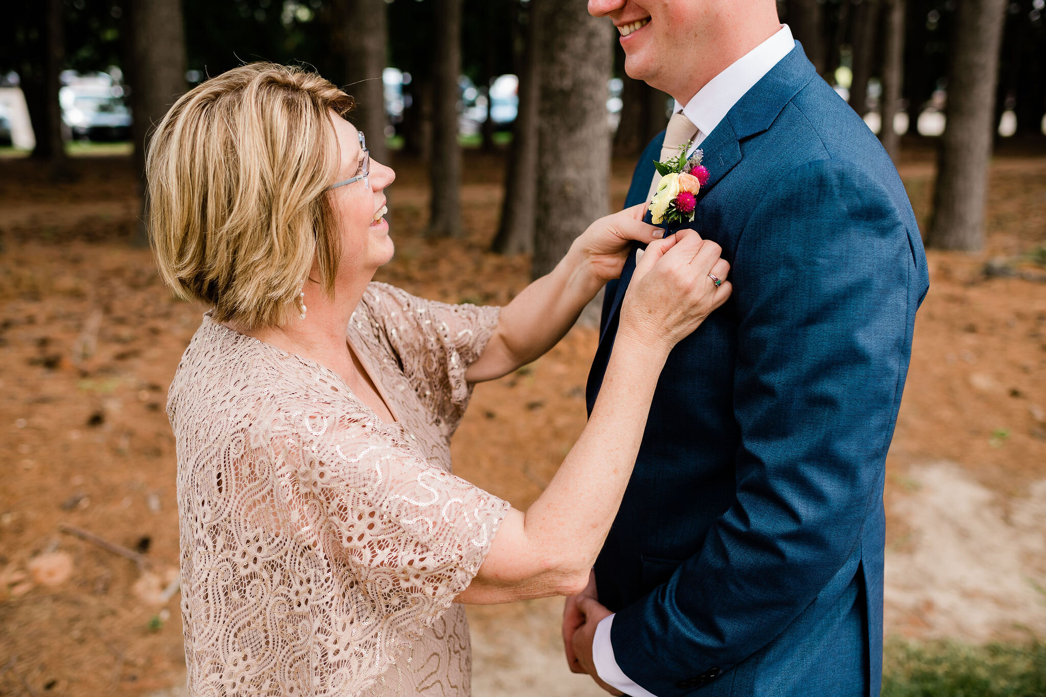 Mother of the groom pinning groom's boutonniere on