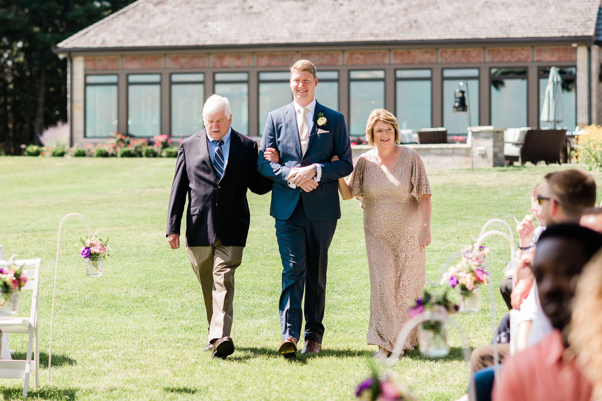 Groom and his parents walking down the aisle