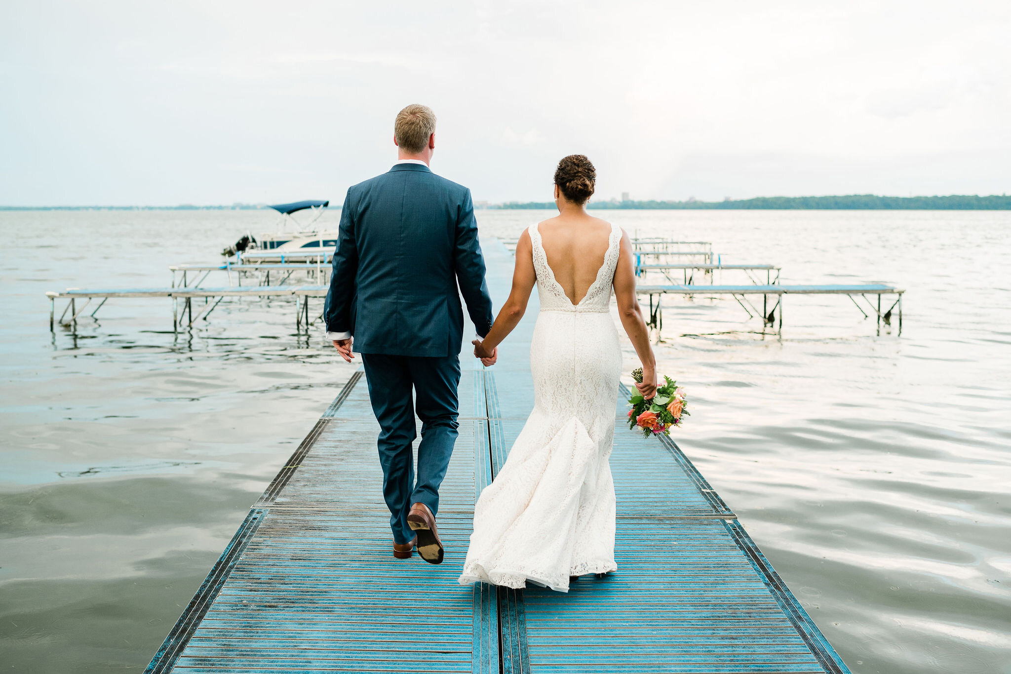 Back view of bride and groom walking down a dock