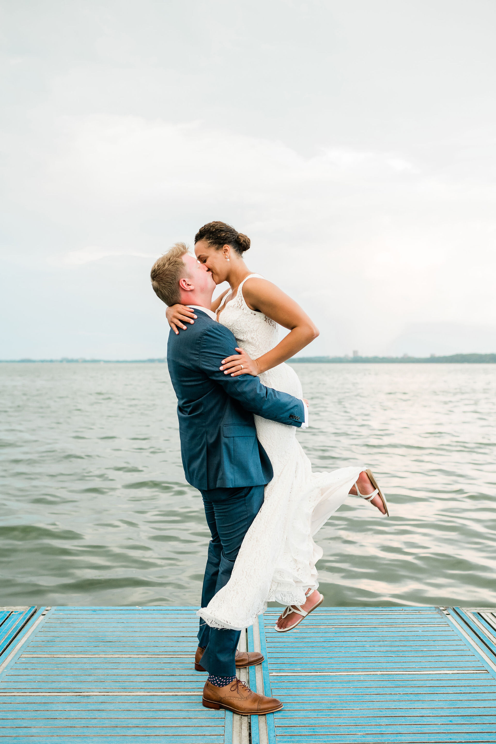Groom lifts bride up on the dock