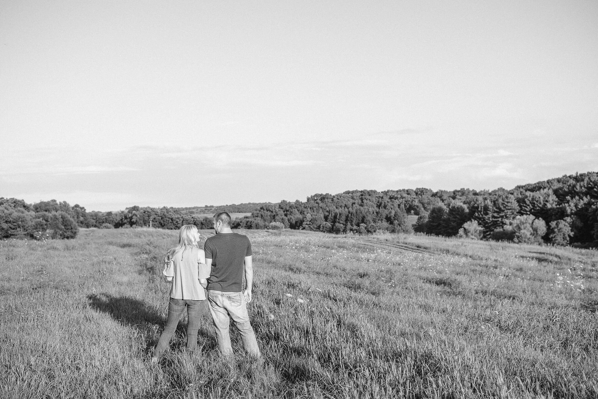 Engaged couple walking through a field