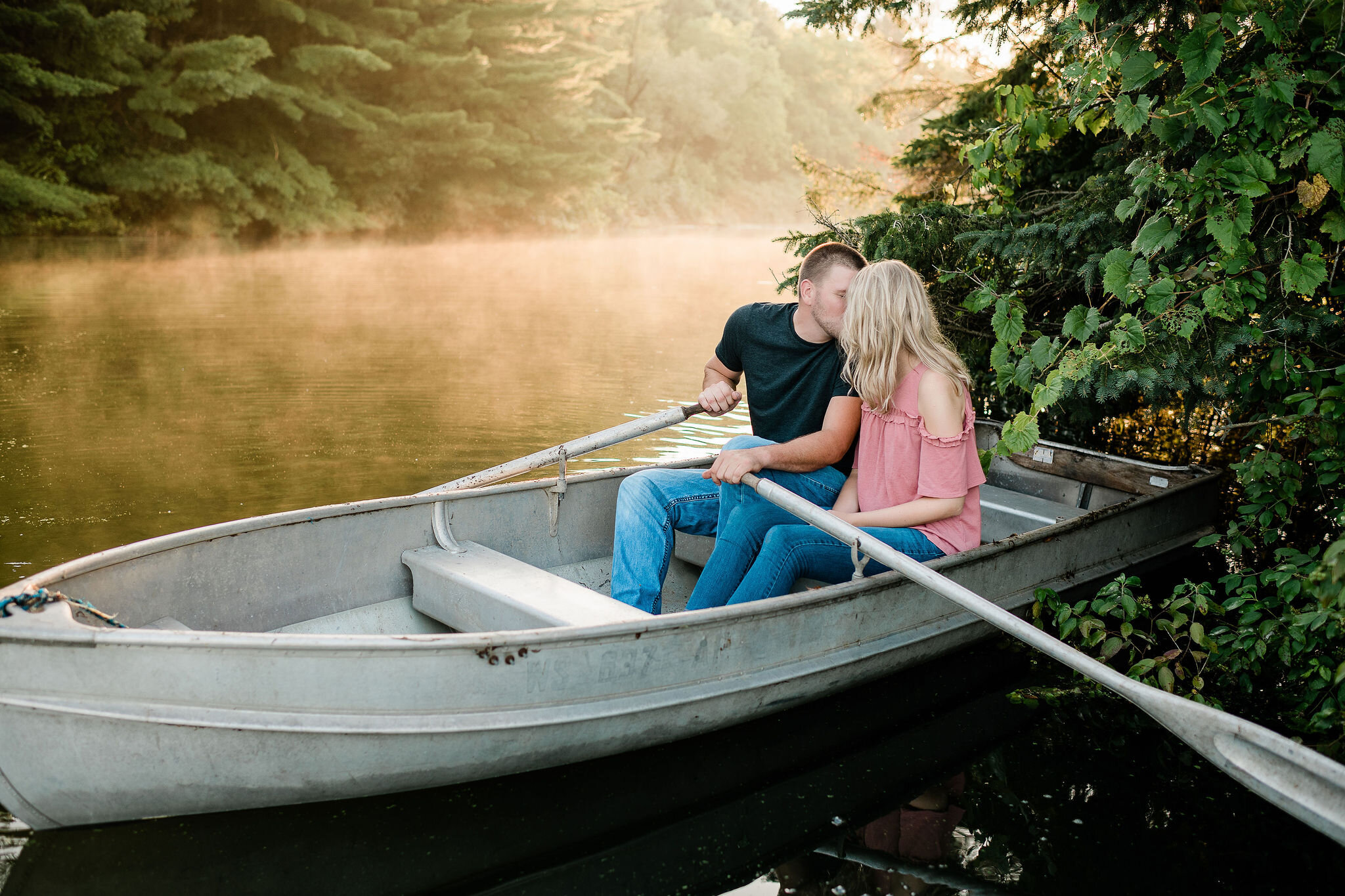 Engaged couple kissing in a canoe