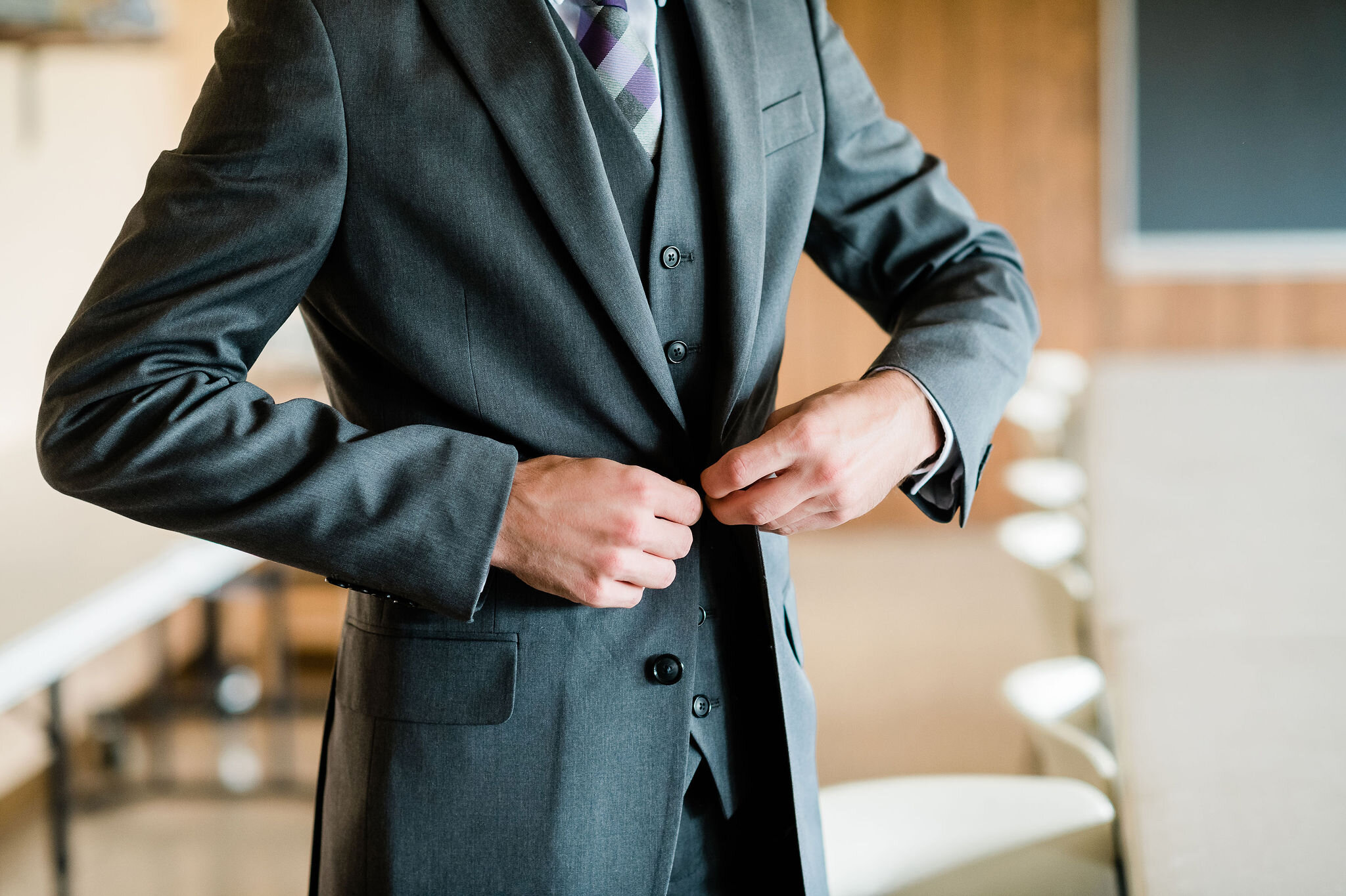 Groom buttoning up his suit jacket