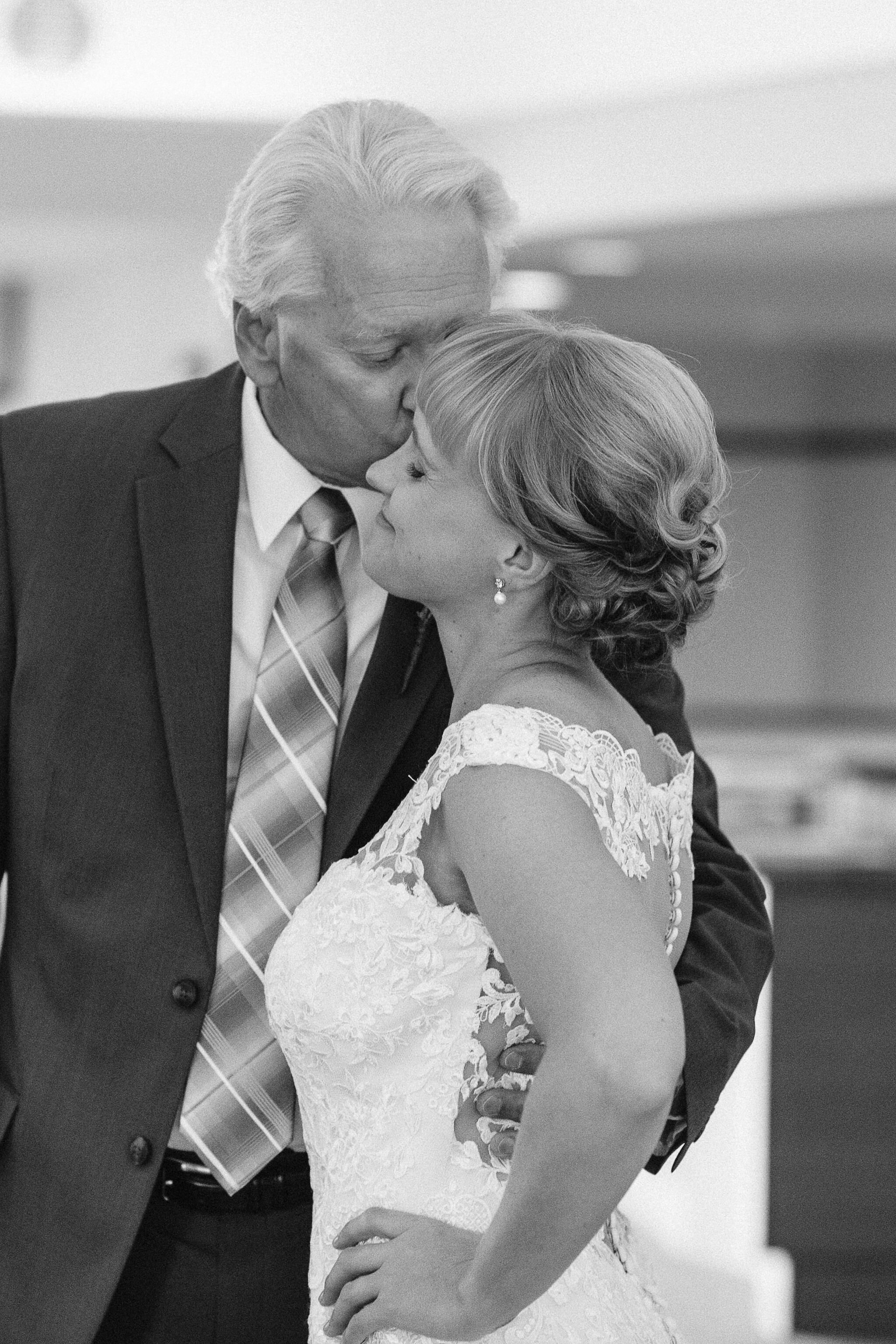Father of the bride kissing her on the forehead