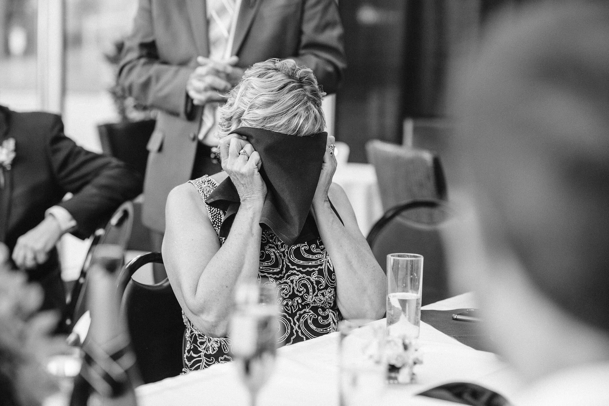 Mother of the bride covers her face with a linen napkin