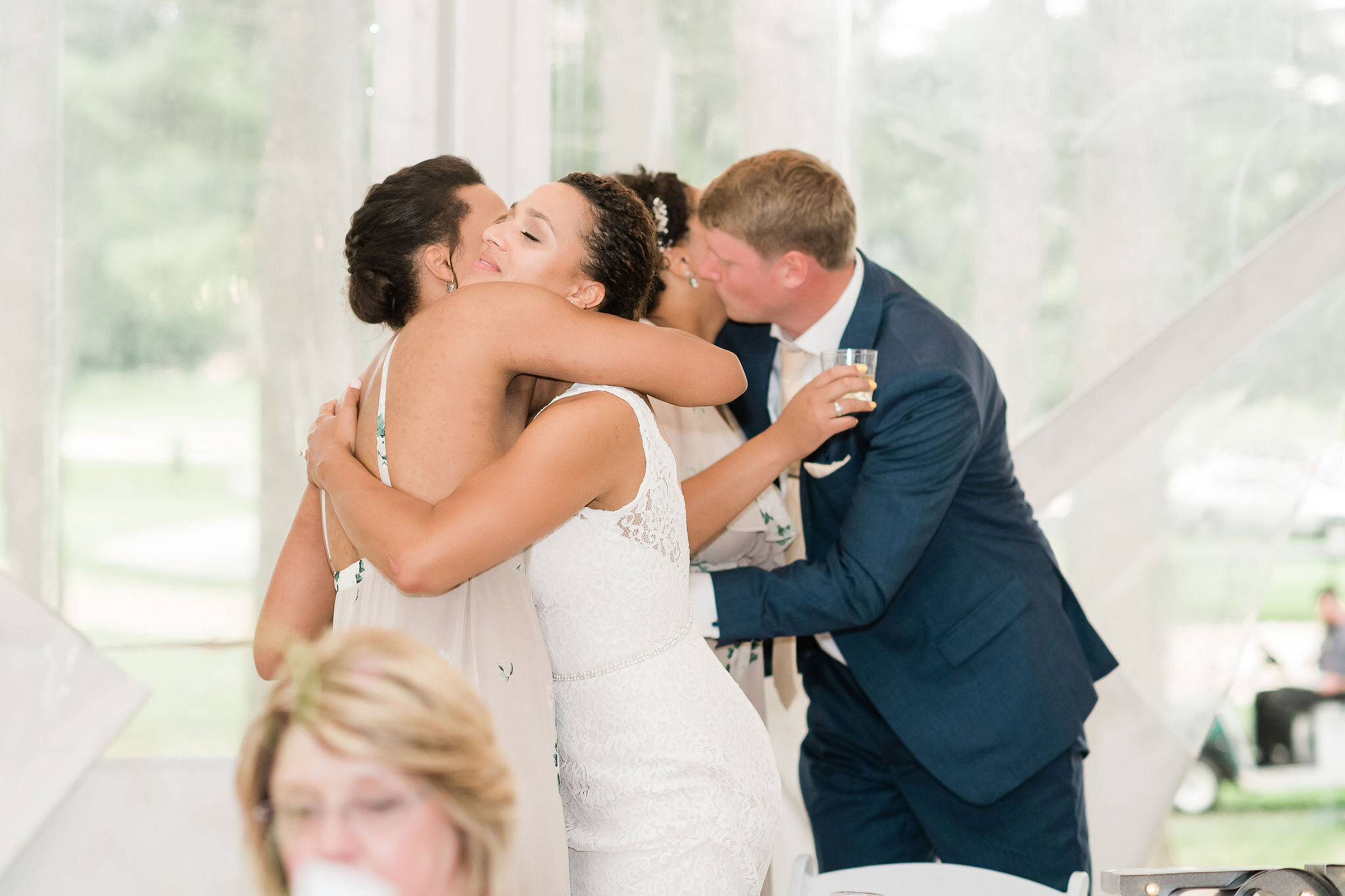 Bride and groom hug bride's sisters