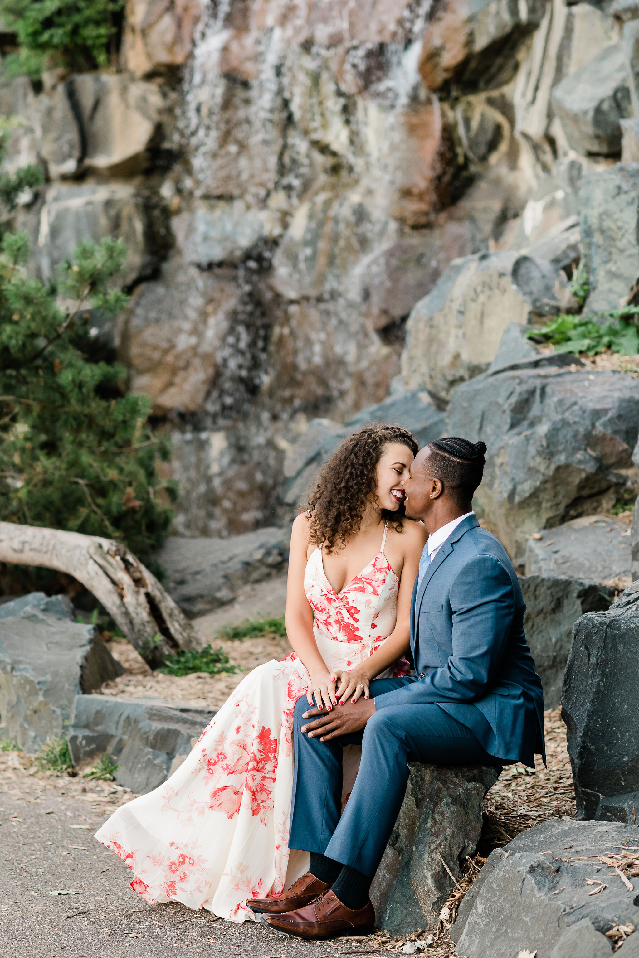 Engaged couple kissing in front of a waterfall