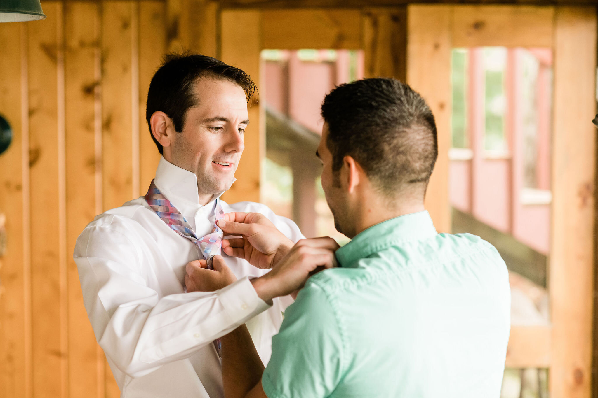 Best man helping groom put his tie on