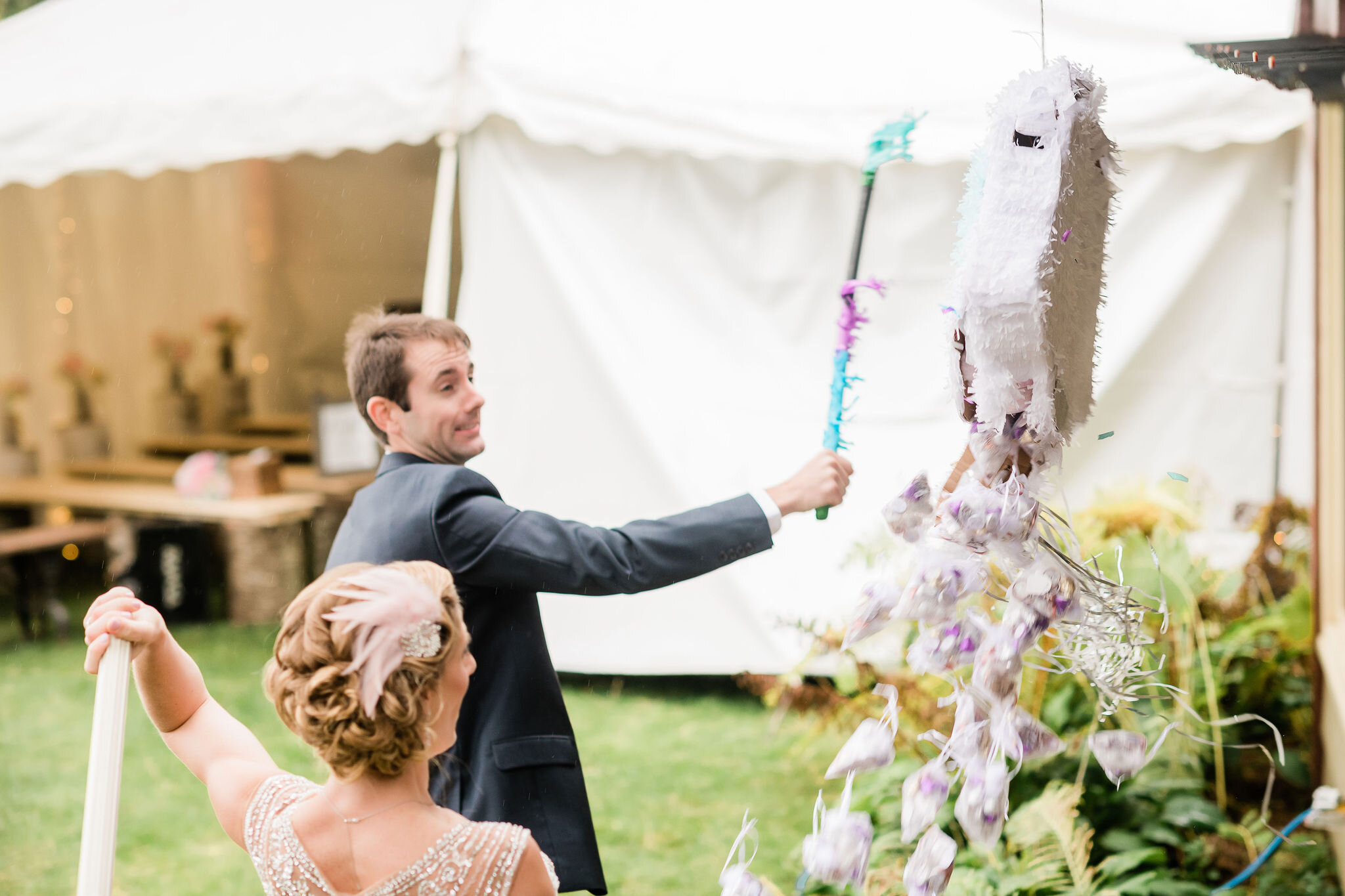 Groom and bride hitting piñata