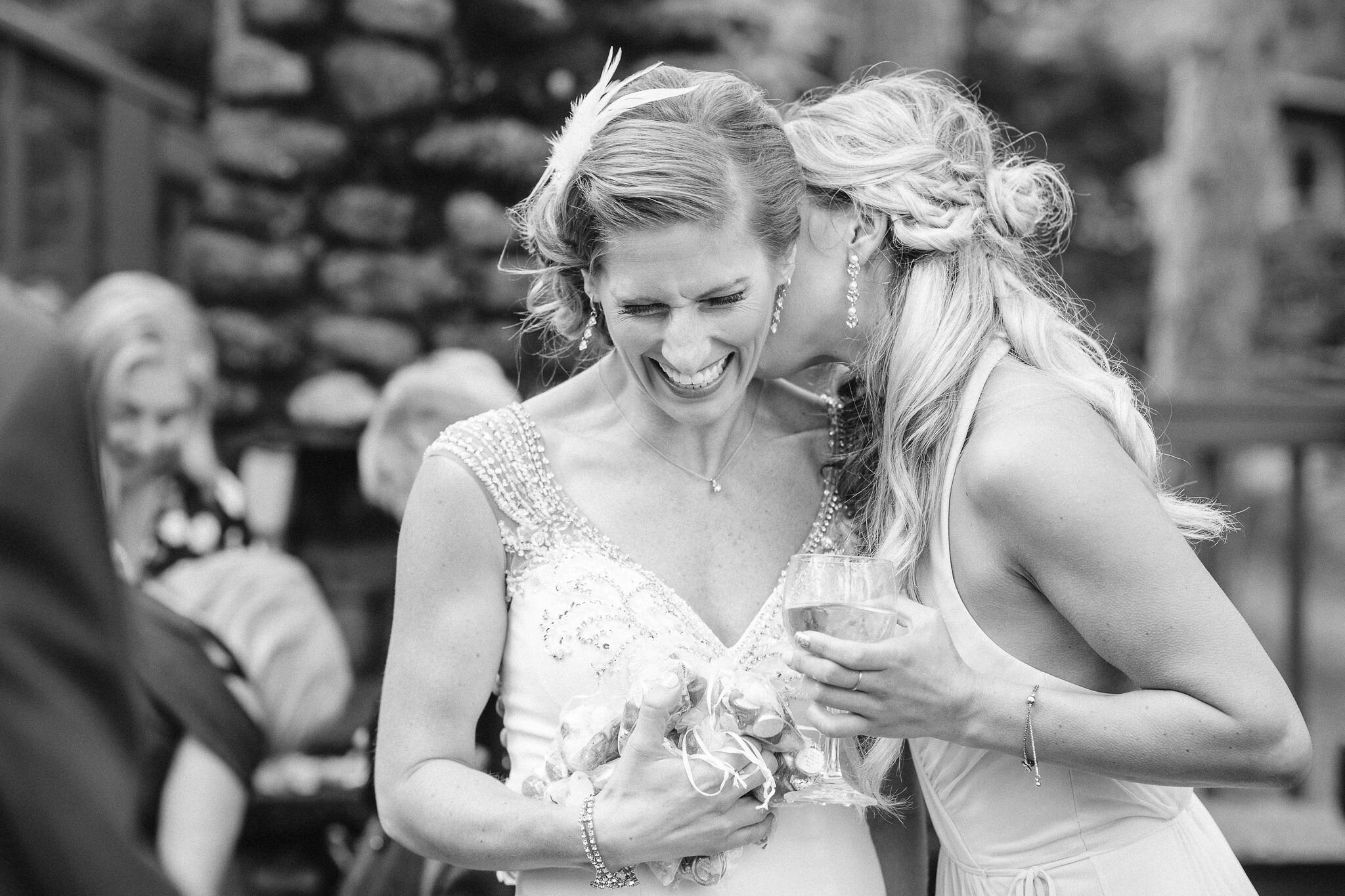 Maid of honor whispering in bride's ear