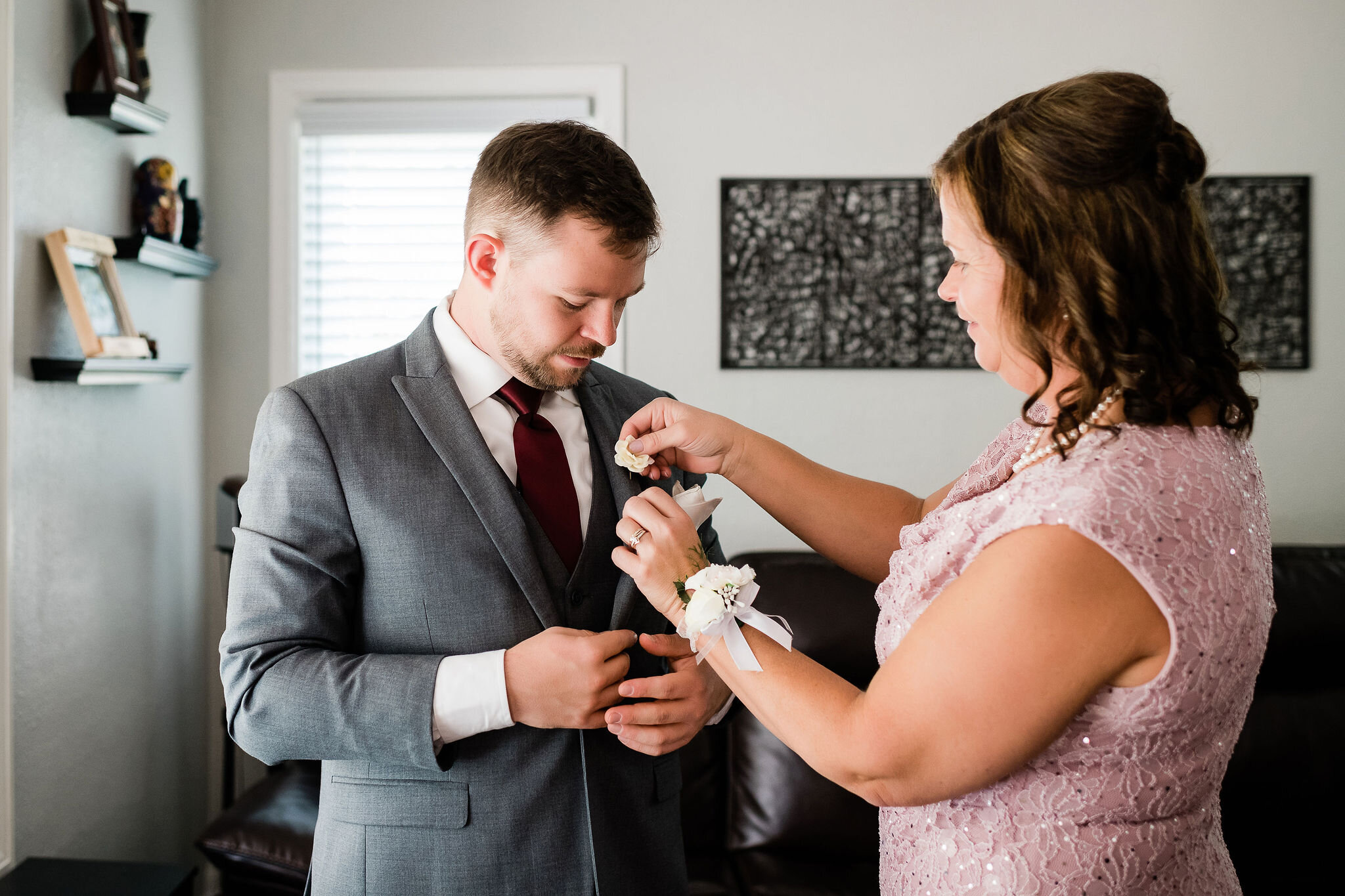 Mother of the groom pinning his boutonniere on