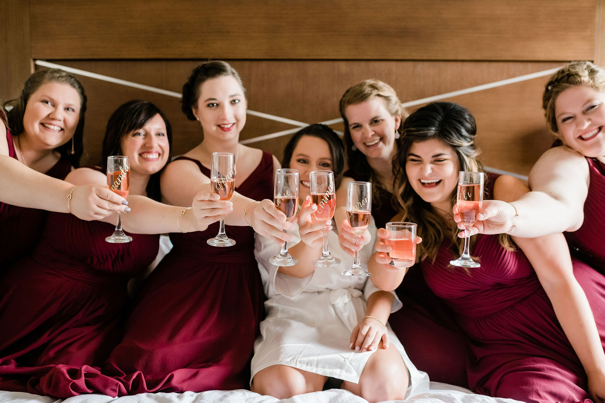Bride and bridesmaids toasting with champagne on the hotel bed